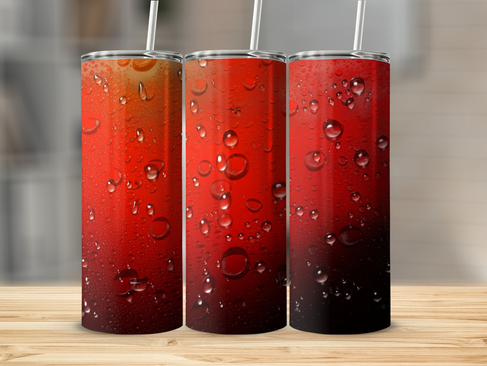 Three red tumblers with condensation and straws on a wooden surface.