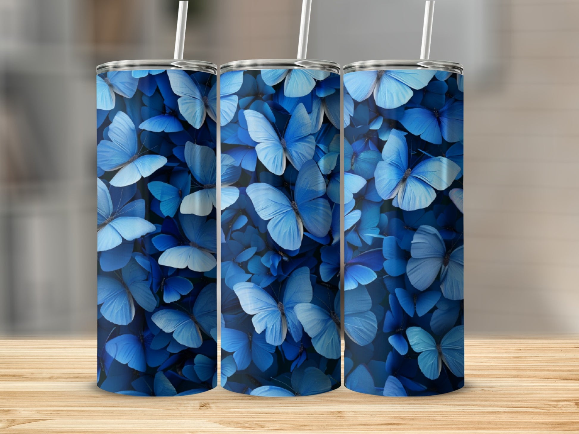 Three blue butterfly patterned tumblers displayed on a wooden surface.