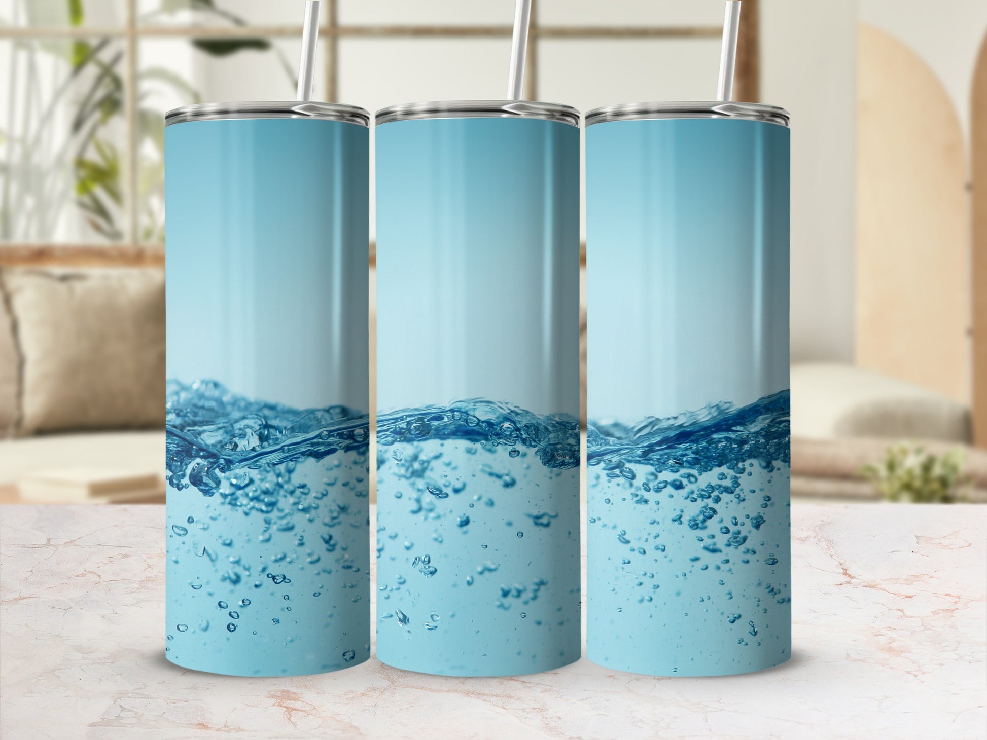Three tumblers with blue water and bubble graphics on a marble surface.