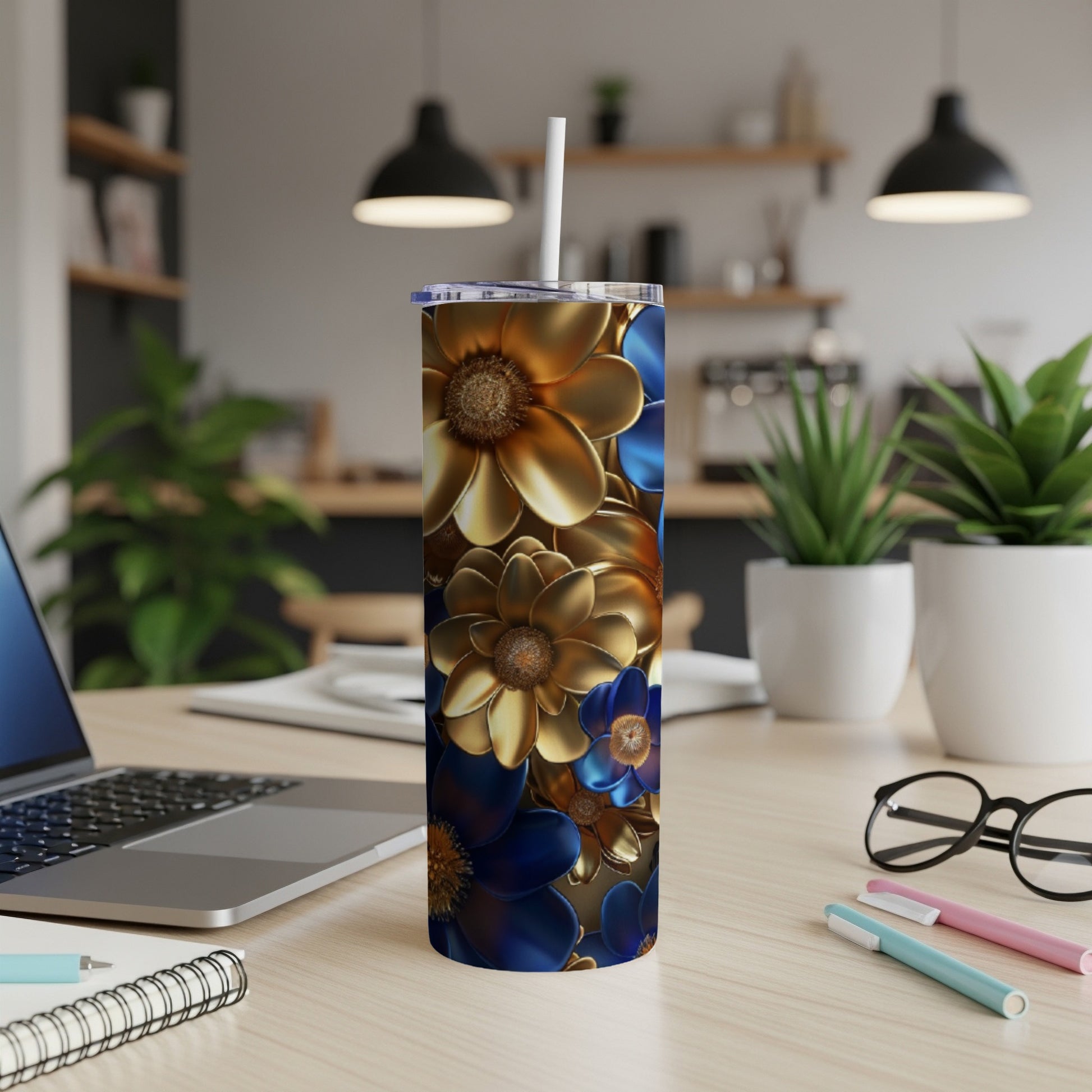 Blue and gold floral tumbler with straw on desk next to laptop.