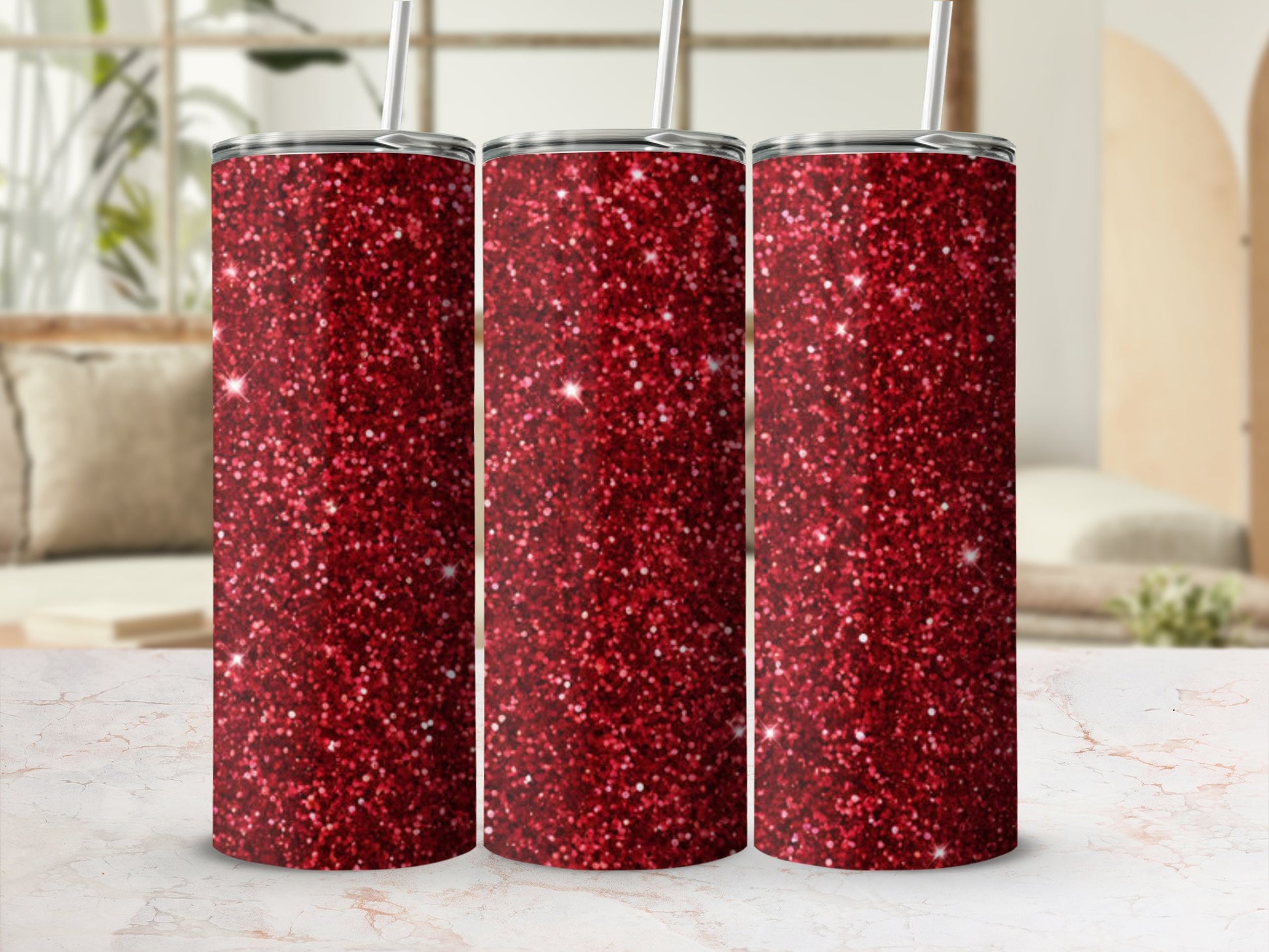 Three red glitter tumblers with straws on a marble surface.