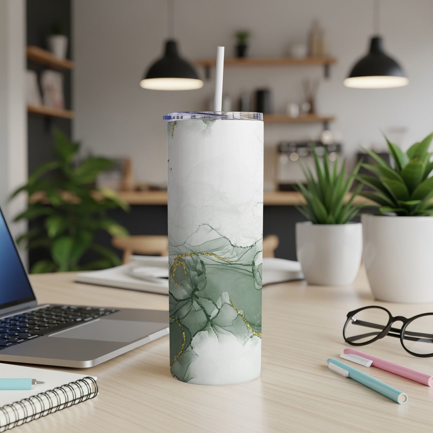 White and green marble-patterned tumbler with gold accents on a desk.