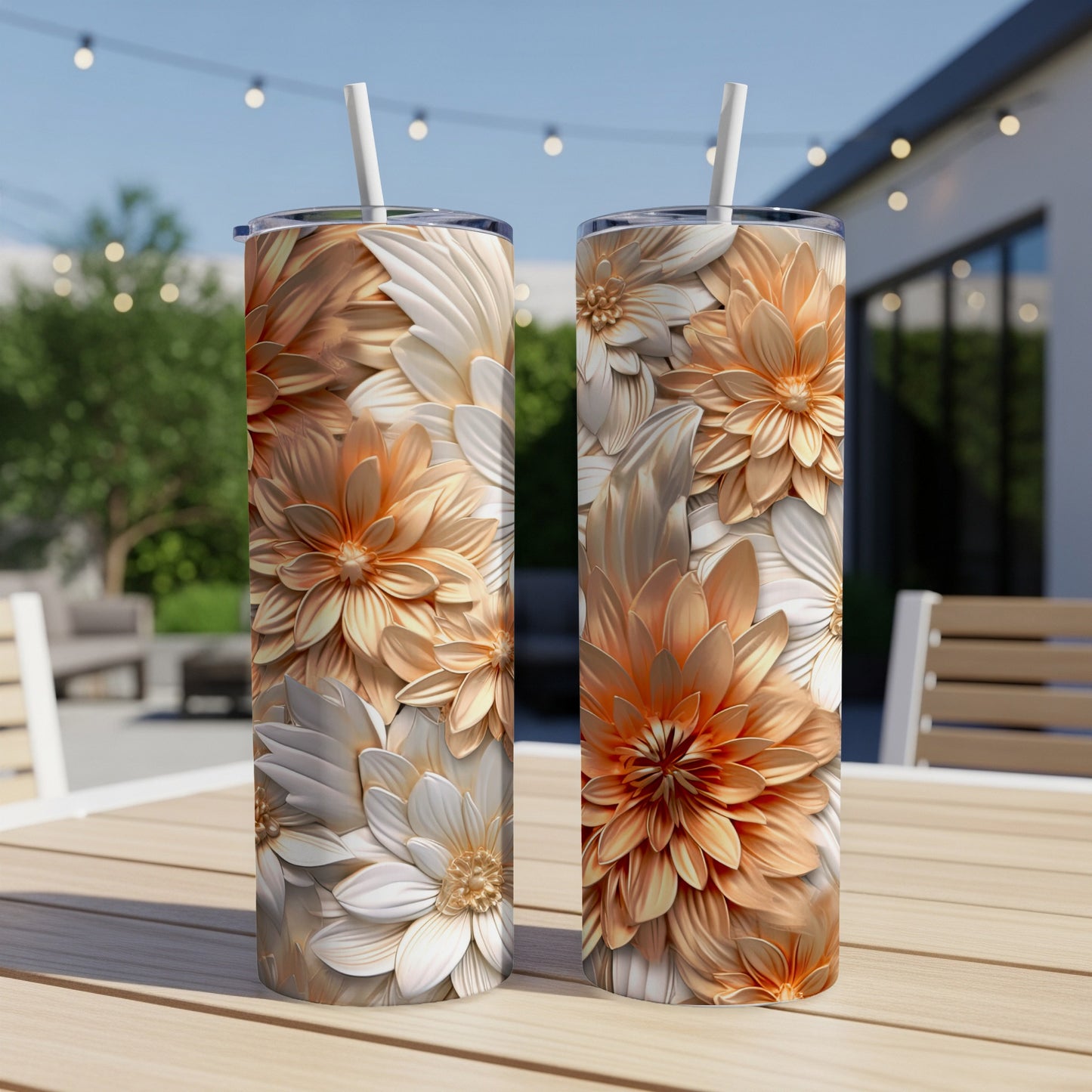 Two tall tumblers with intricate floral designs and straws on a table.