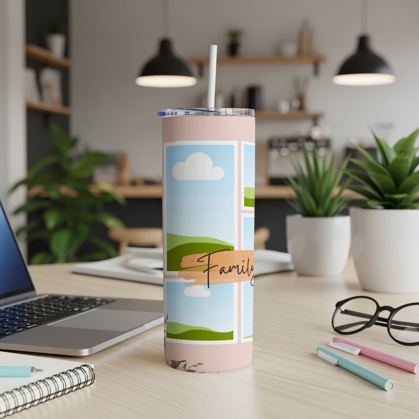 Pink tumbler with "Family" text and landscape photos on a desk.