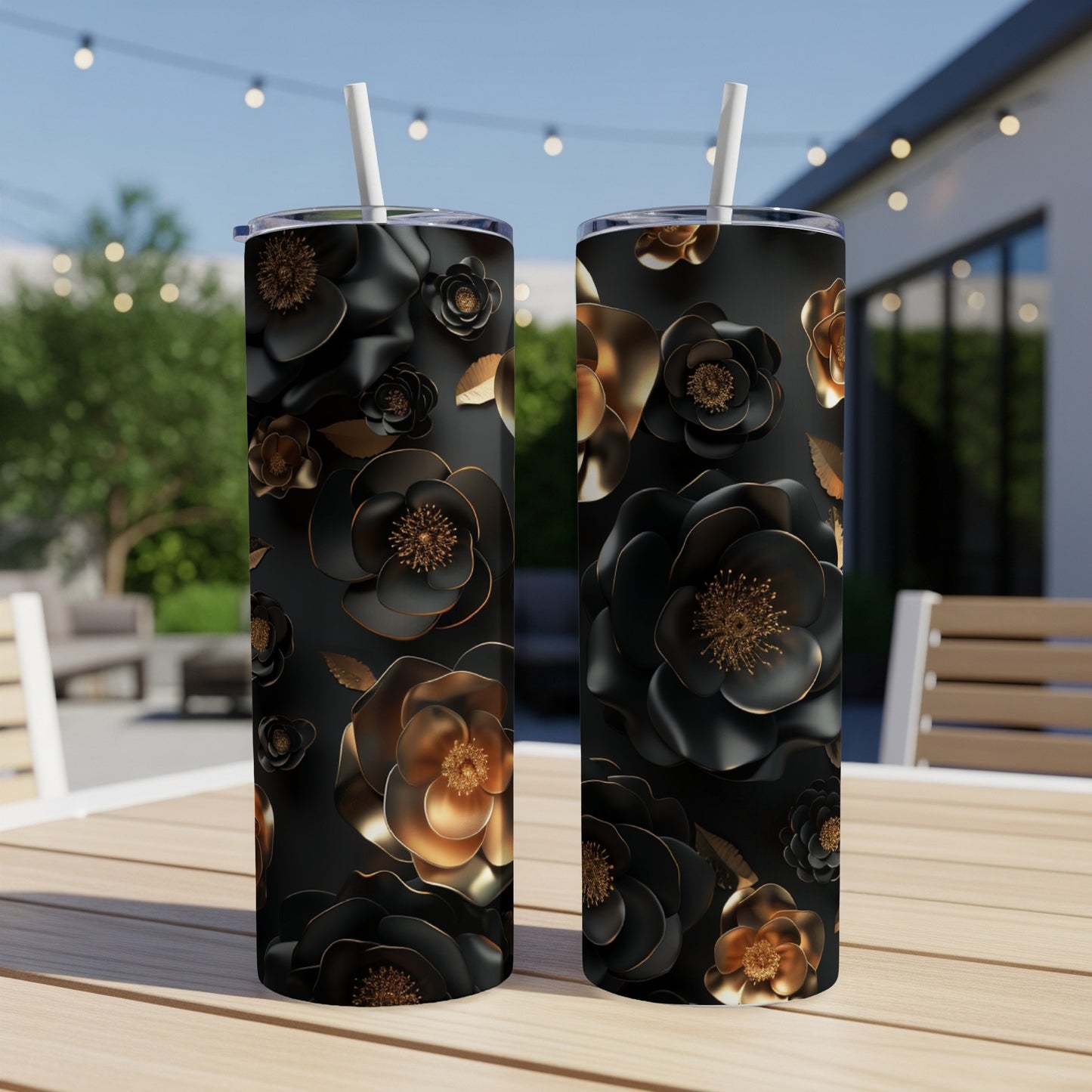 Two black tumblers with gold and black floral designs on an outdoor table.