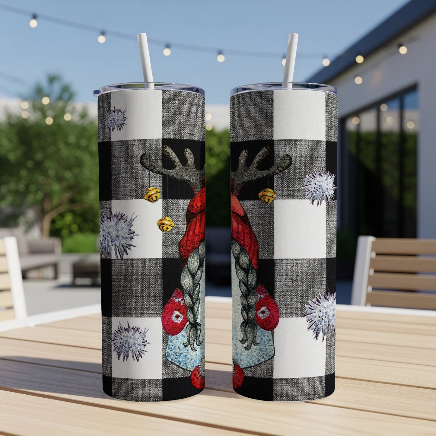 Two tumblers with buffalo plaid and a gnome illustration, set outdoors.