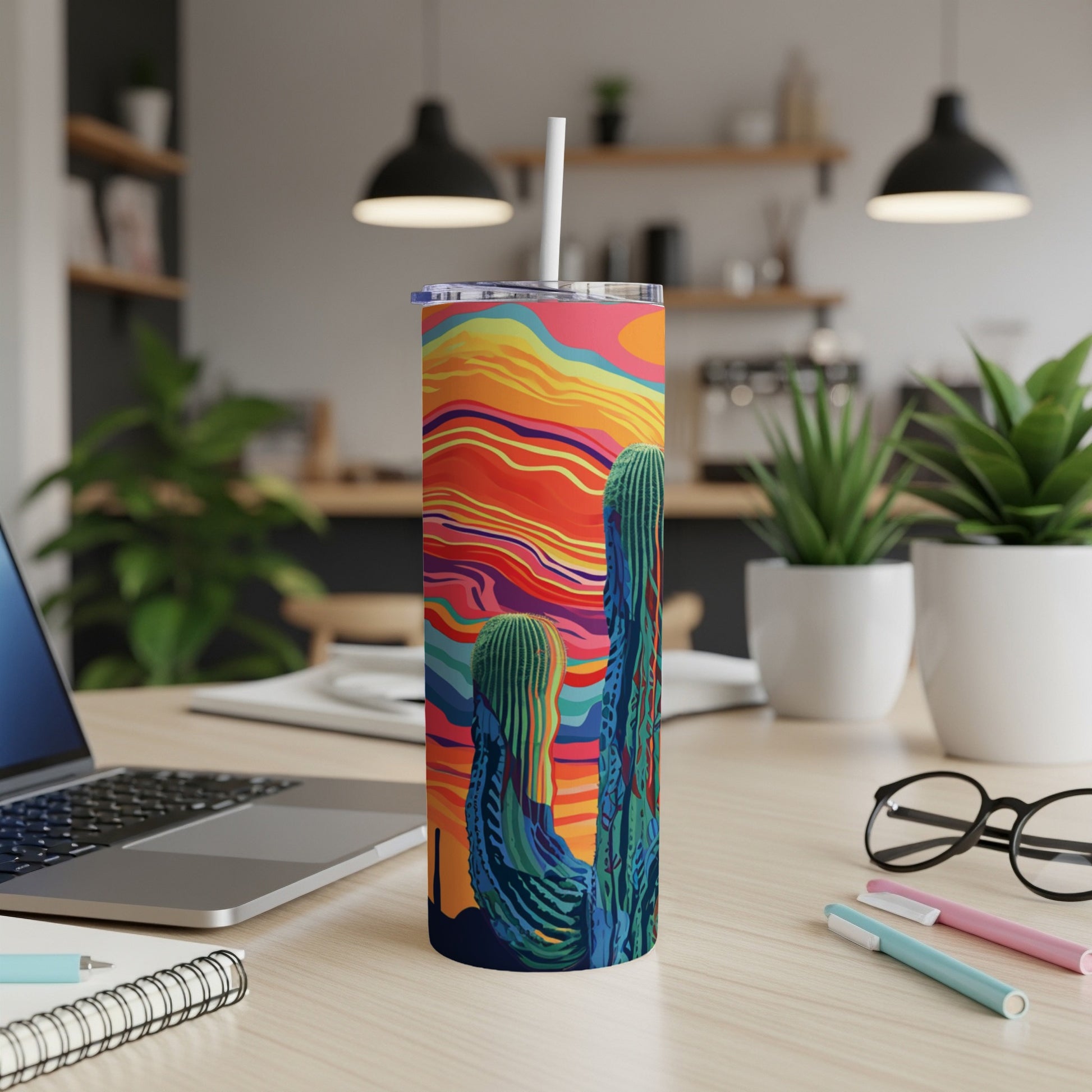 Colorful desert sunset artwork on a tumbler with a straw, on a desk.