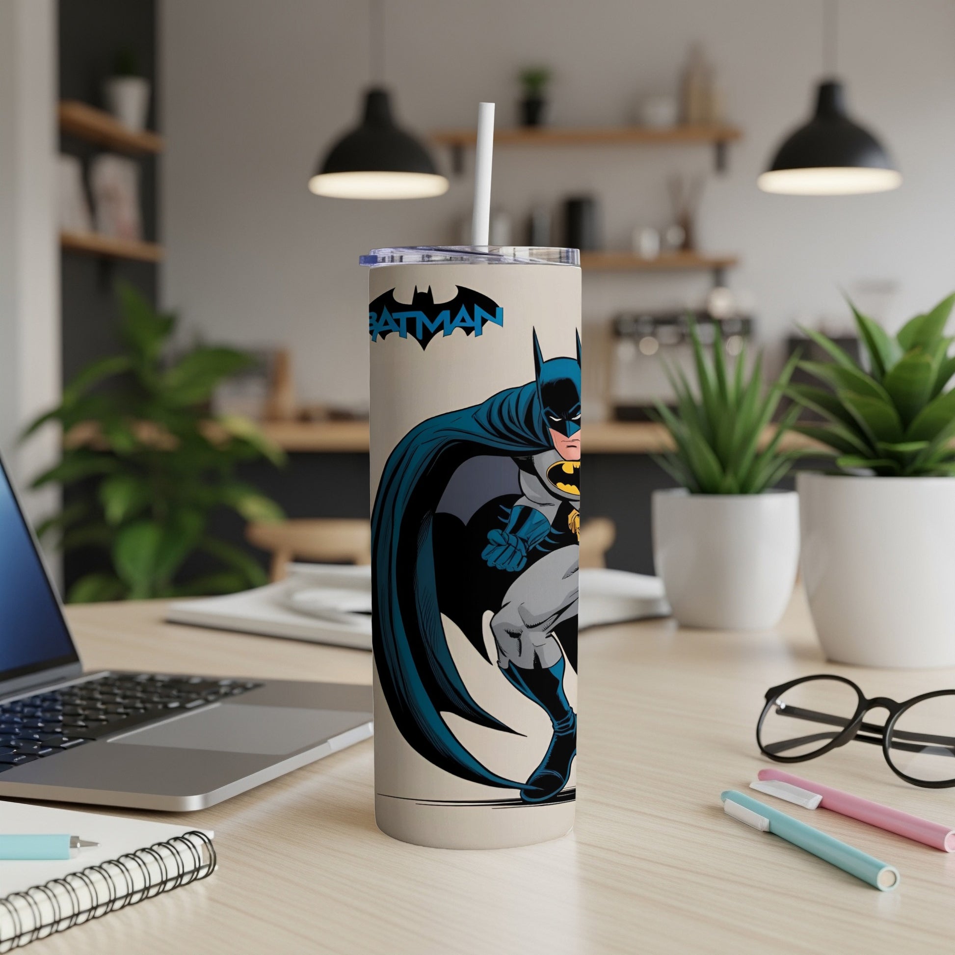Batman tumbler with straw on a desk next to a laptop.