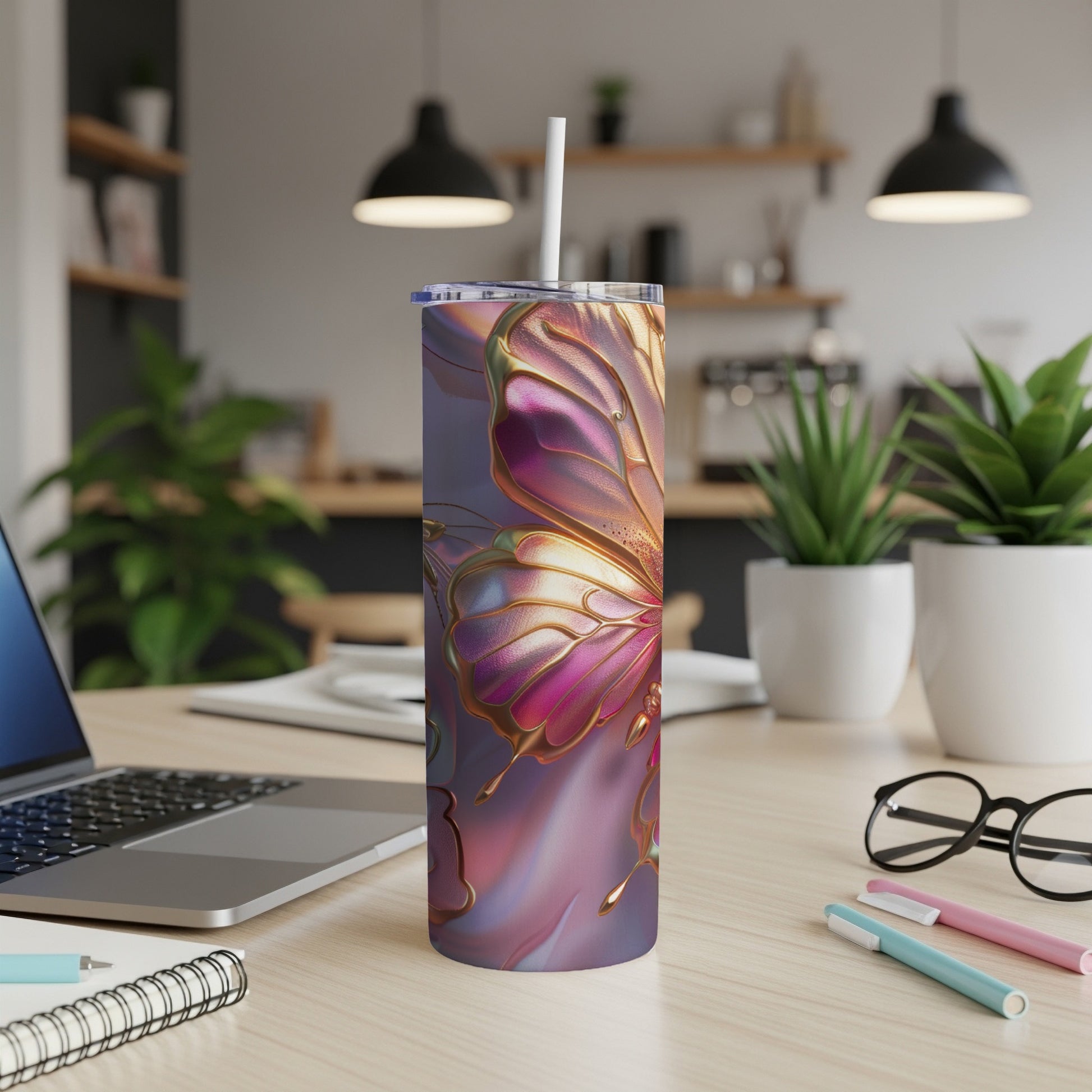 Pink and gold iridescent butterfly tumbler with straw on a desk.