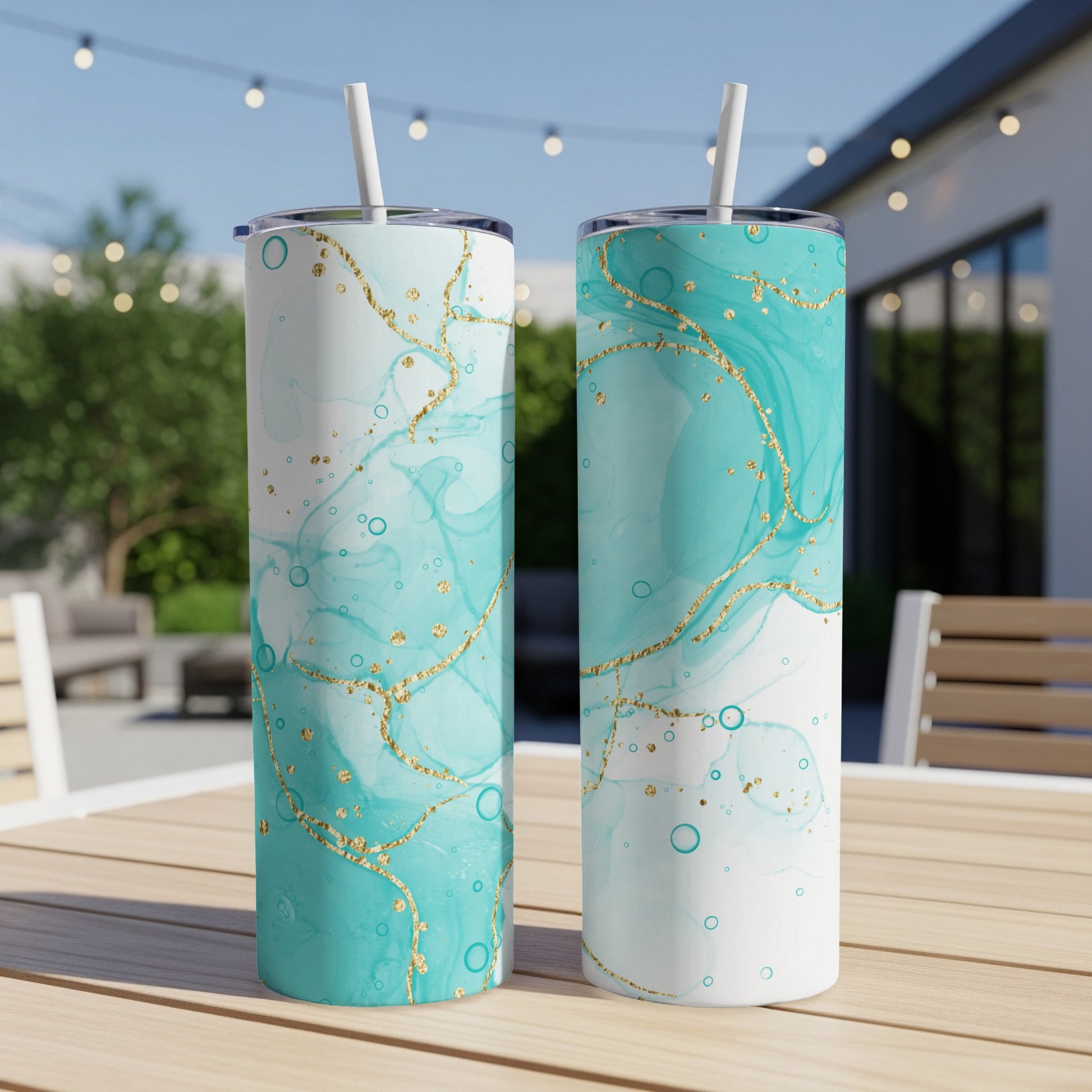 Two tall, teal and white tumblers with gold marbling and straws.