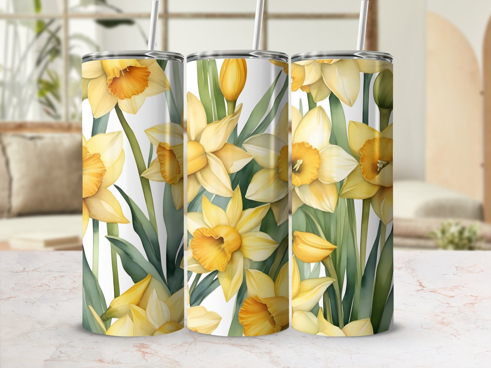 Three tumblers adorned with a pattern of yellow daffodils and green leaves.