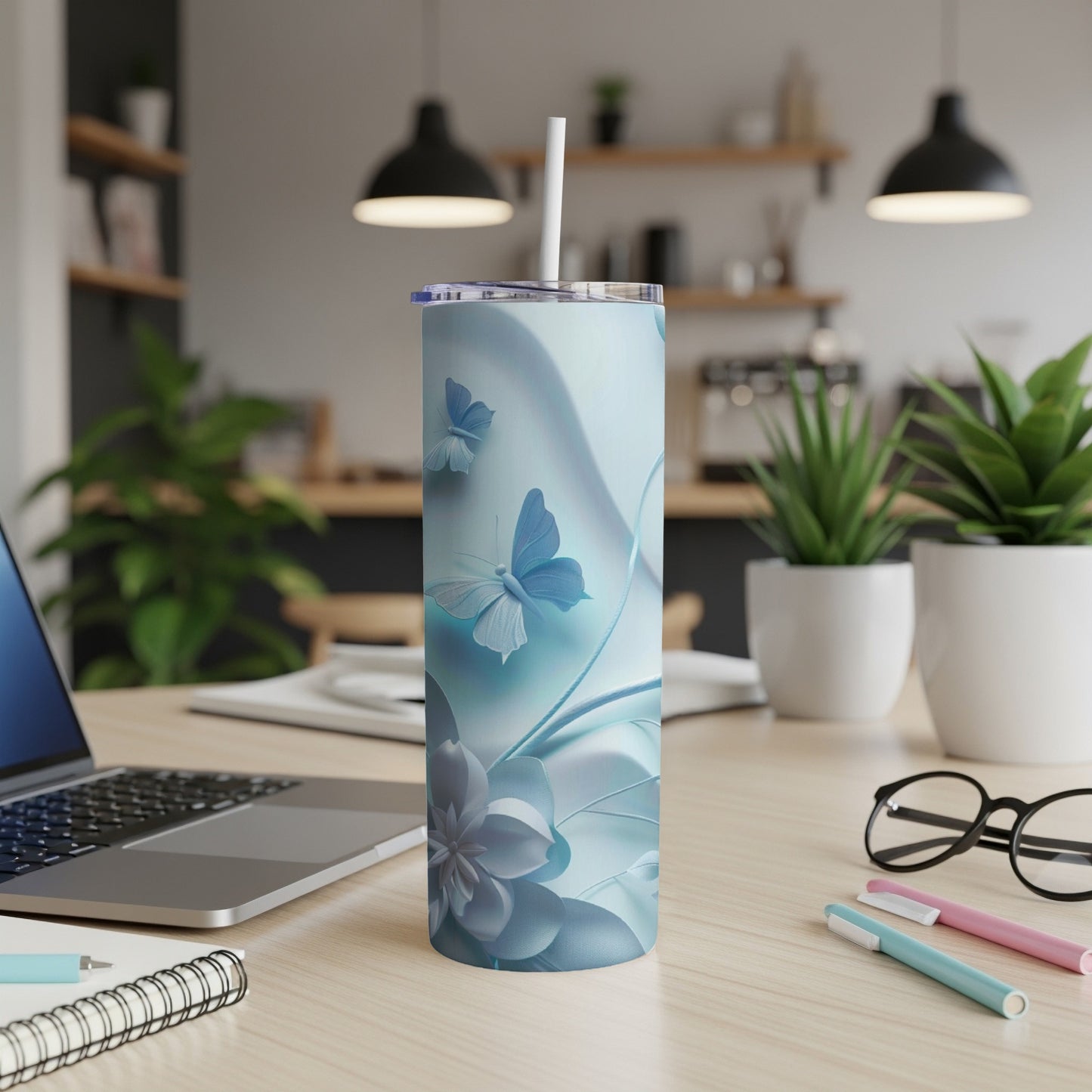 Blue floral and butterfly pattern on a skinny tumbler with a straw.