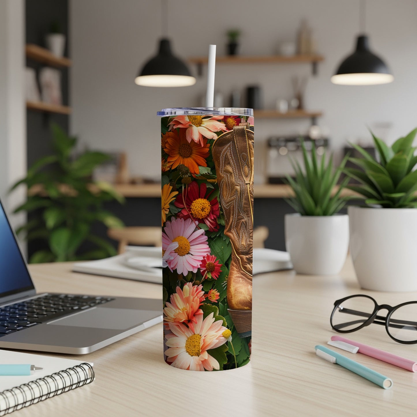 Tall tumbler with floral pattern and cowboy boot detail on a desk.