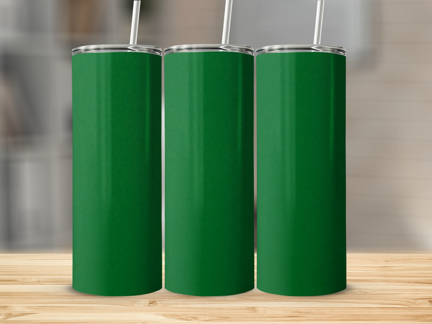 Three plain green tumblers with white straws on a wooden surface.