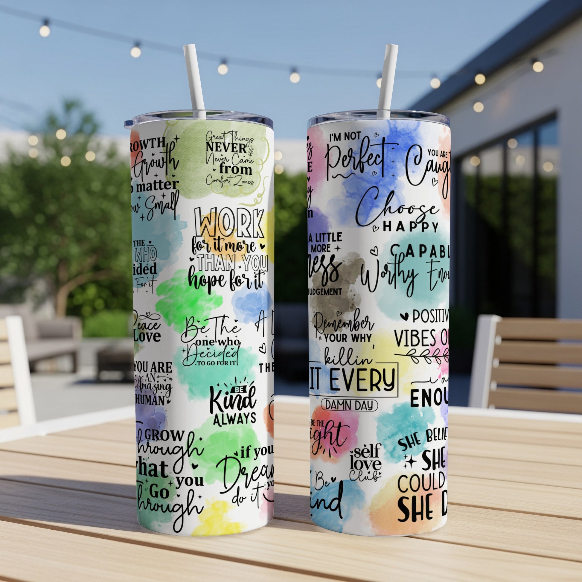 Two tumblers with inspirational quotes and graphics on a wooden table.