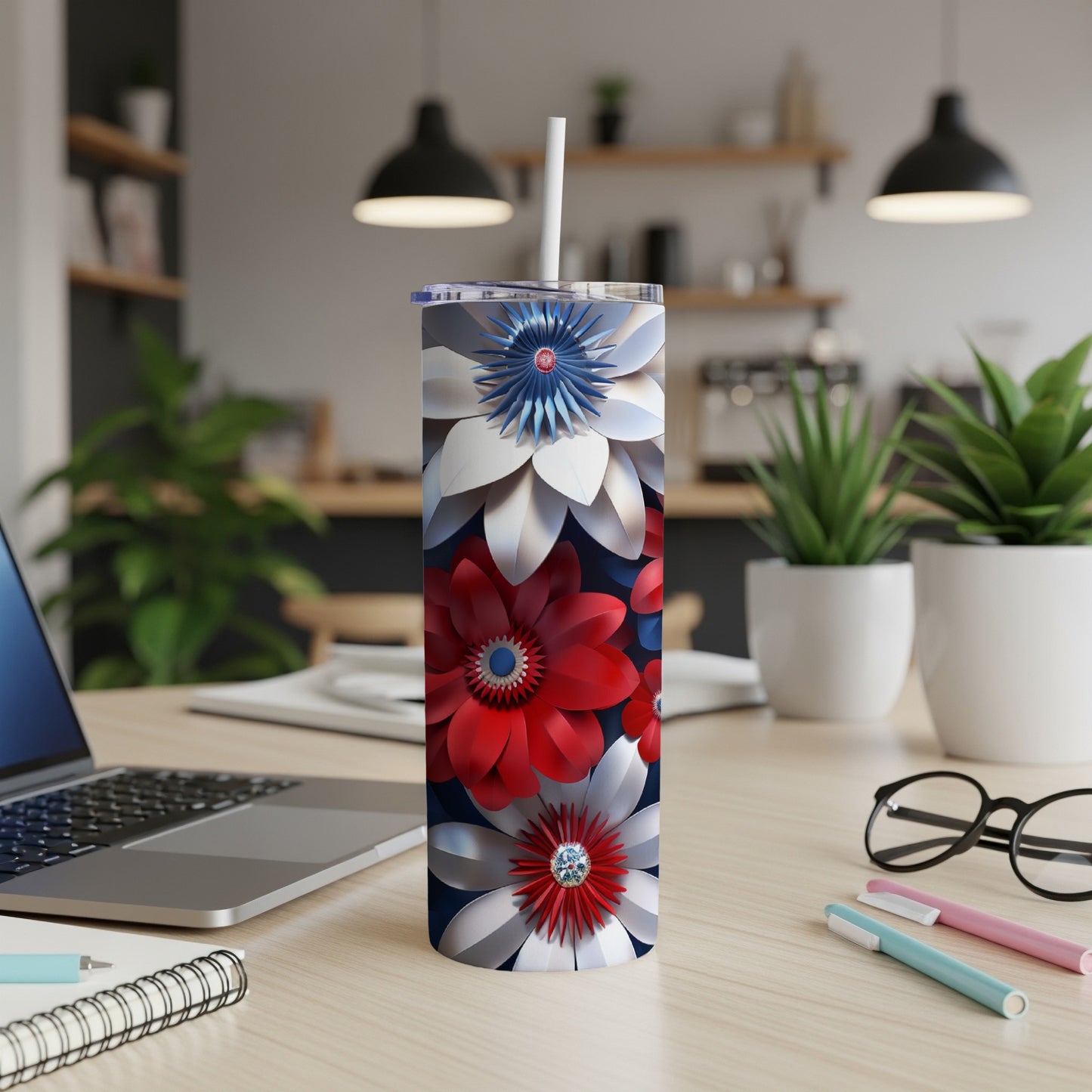 Red, white, and blue floral patriotic tumbler with straw on desk.