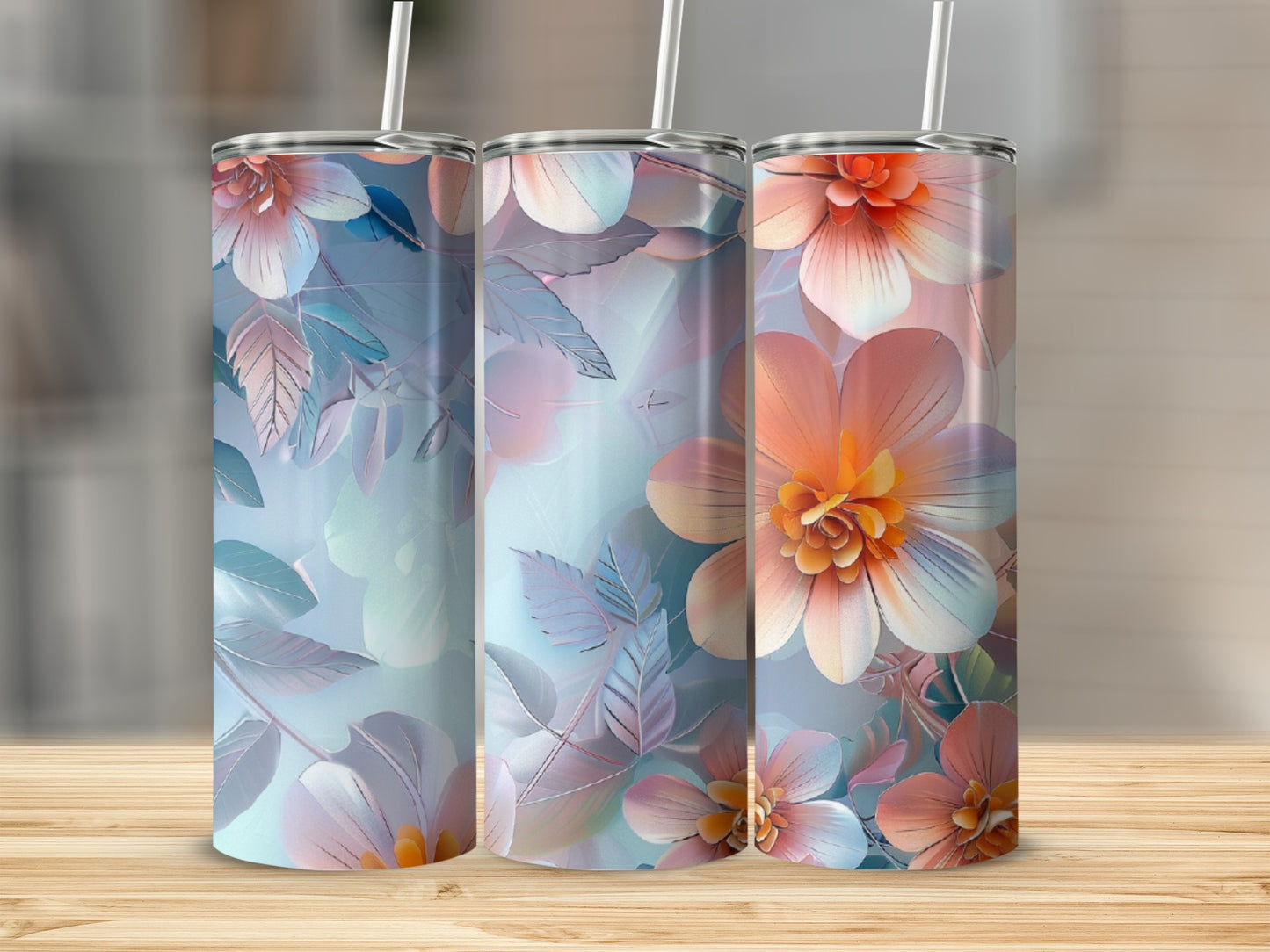 Three floral patterned tumblers with straws on a wooden surface.