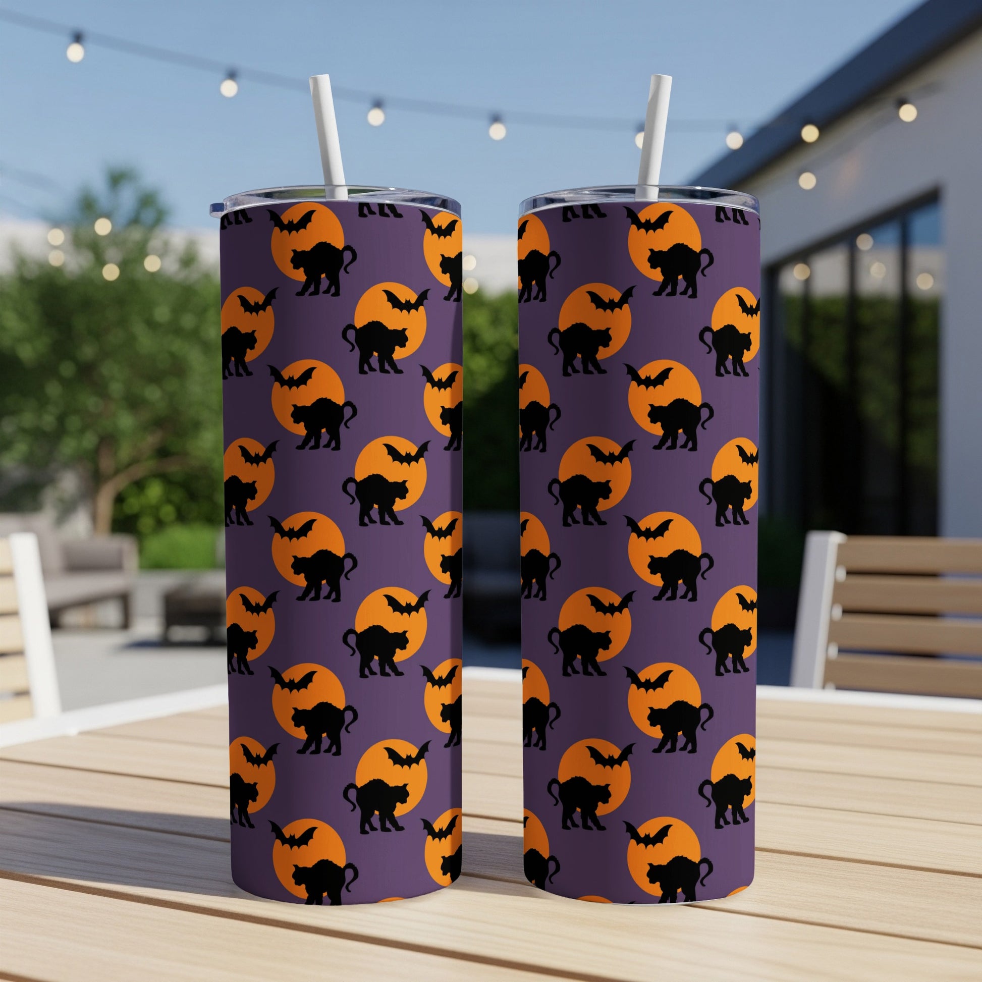 Purple tumbler with Halloween pattern of black cats and bats on orange moons.