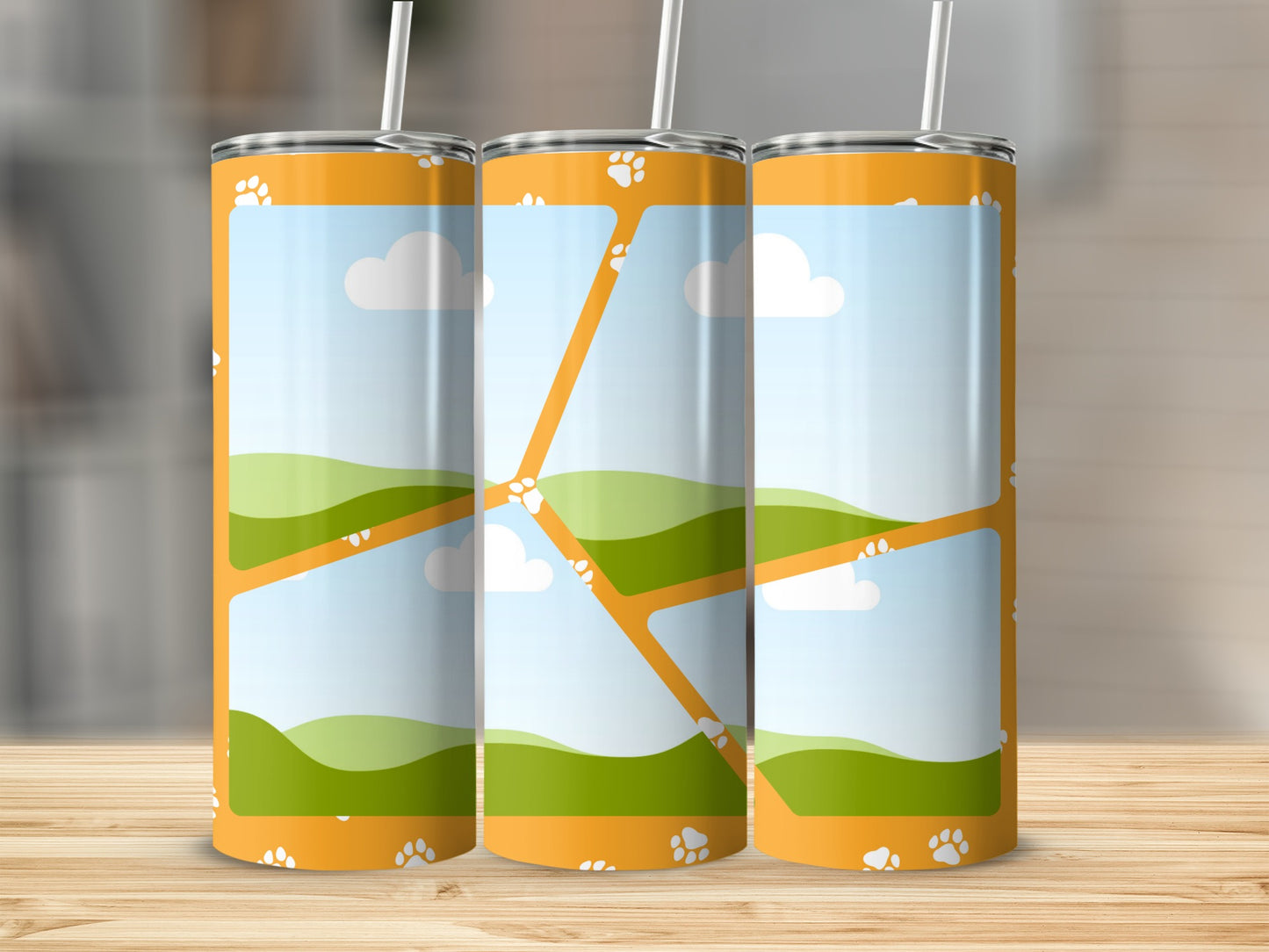 Three orange tumblers with paw print and landscape design.