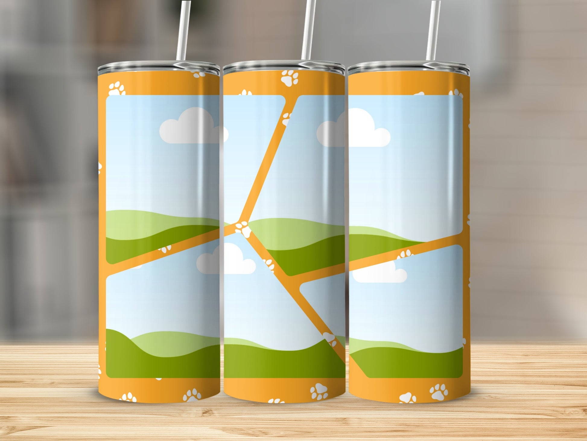 Three orange tumblers with paw print and landscape design.
