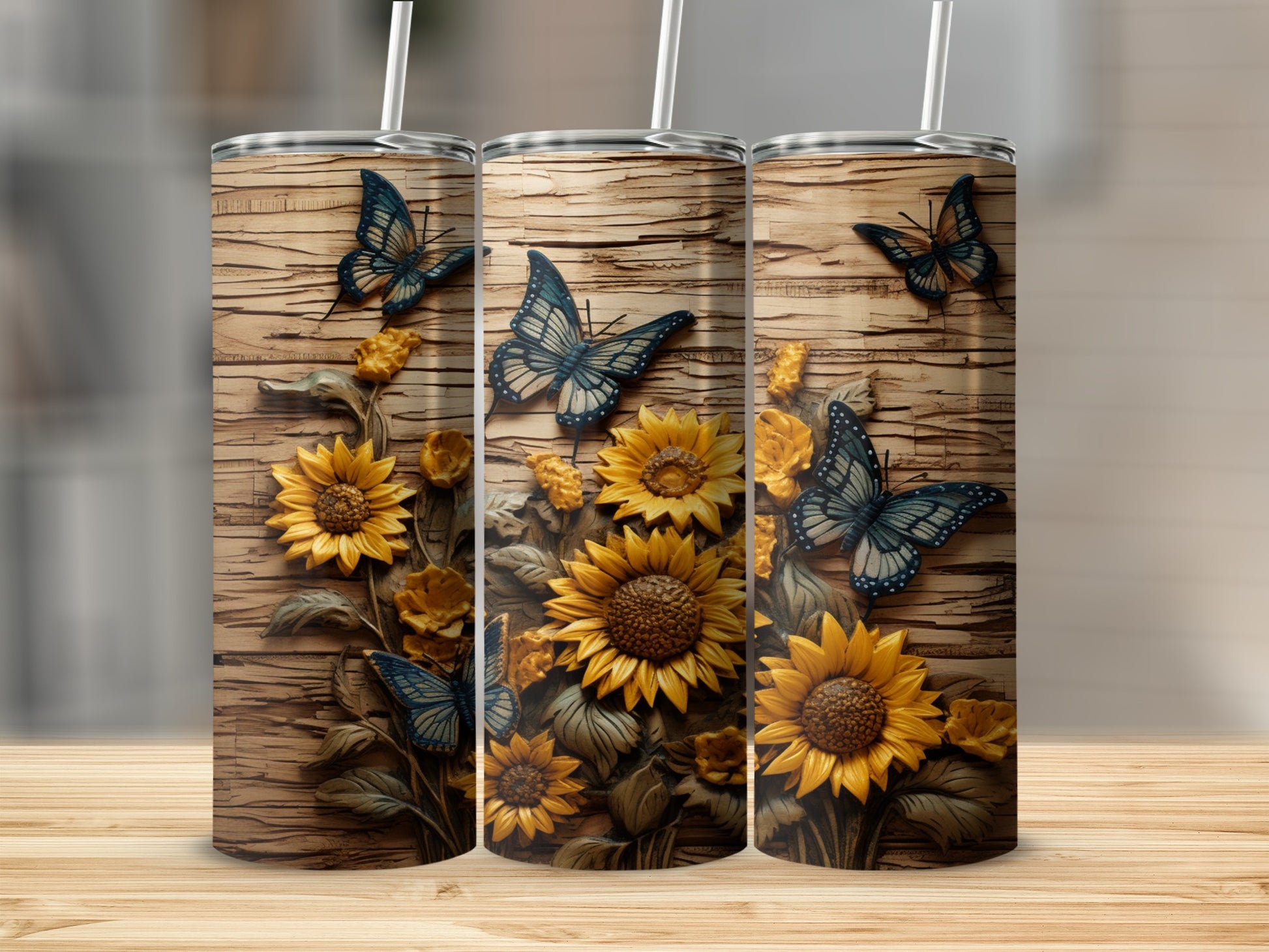 Three tumblers decorated with sunflowers and blue butterflies on a wood grain background.