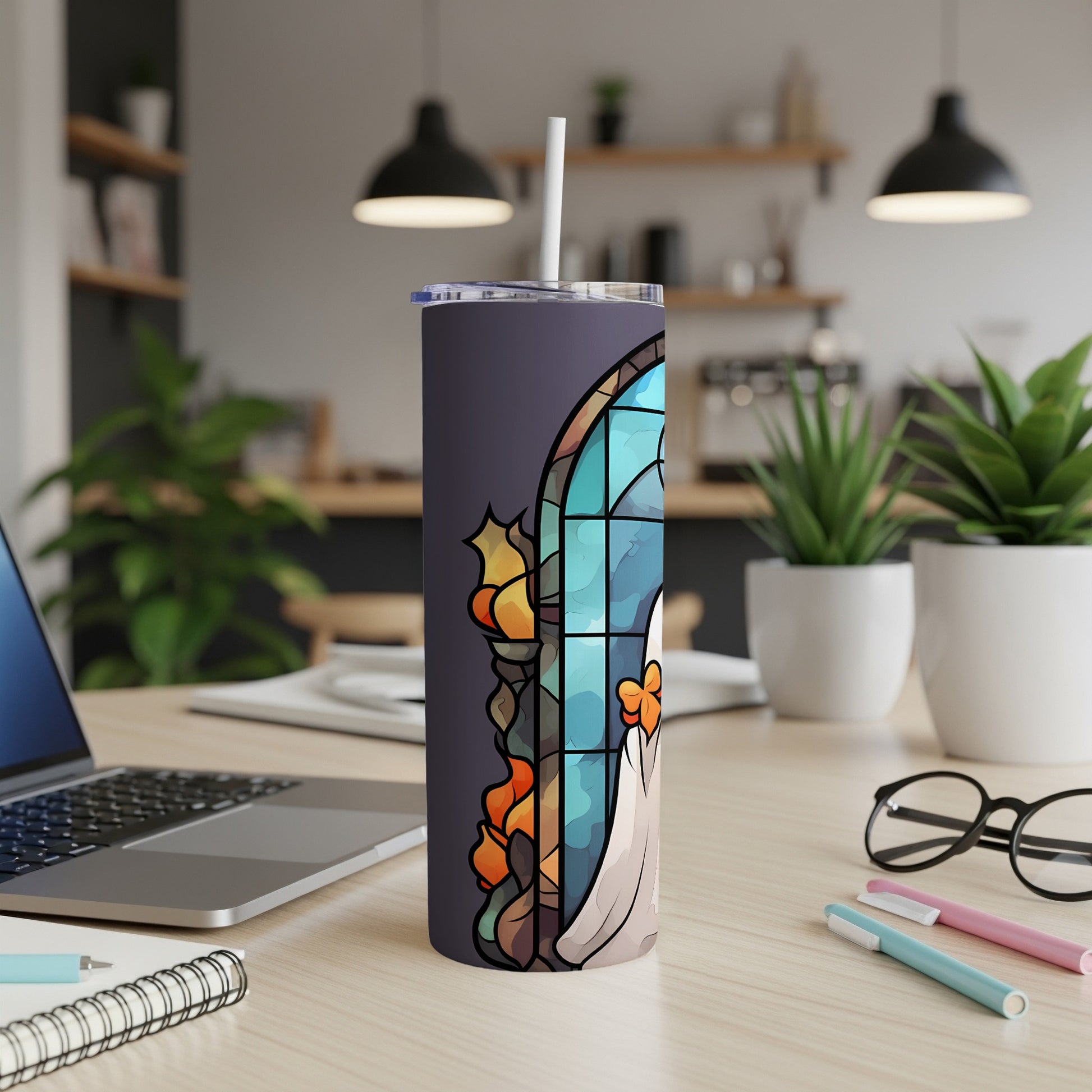 Stained glass ghost tumbler with a straw on a desk.