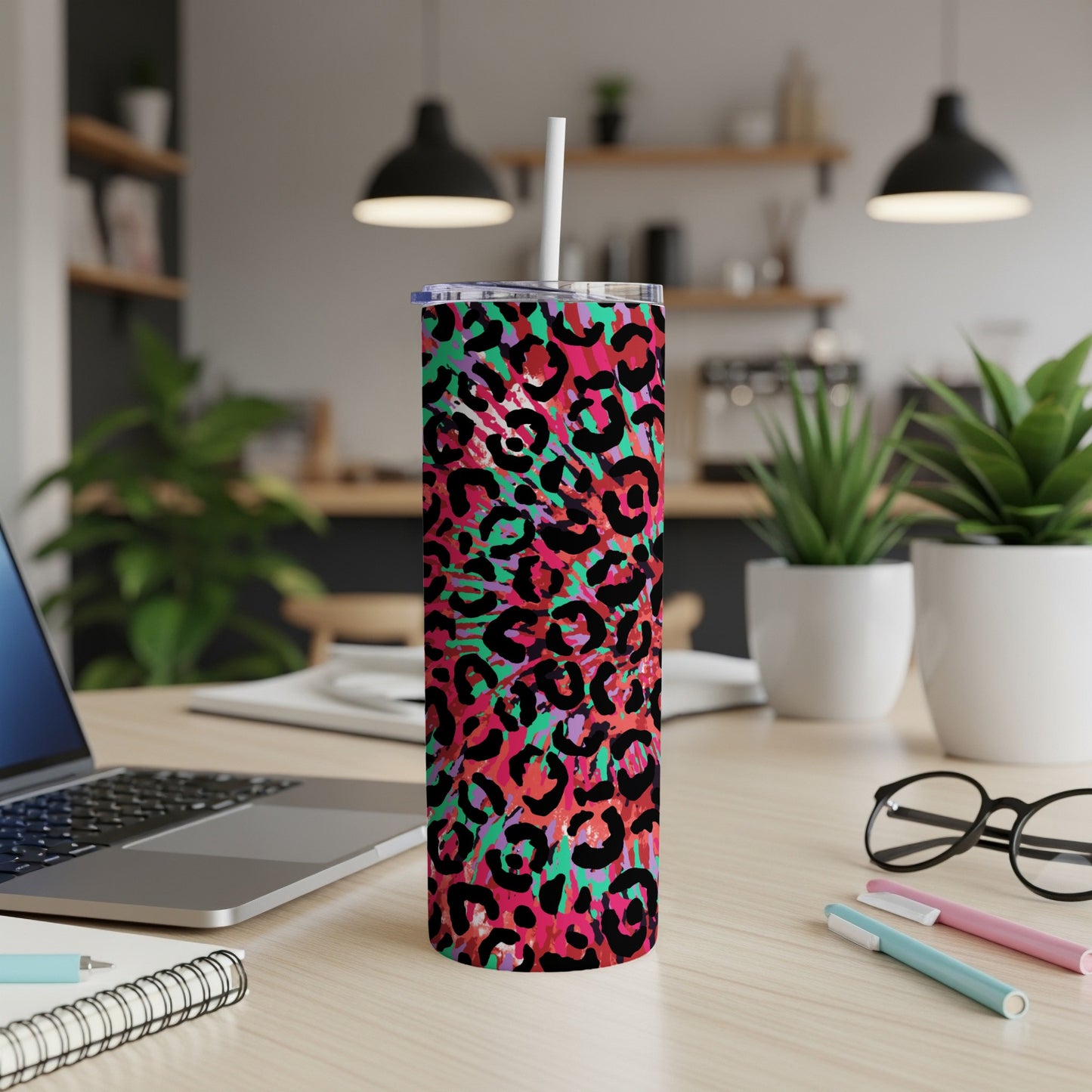 Tumbler with vibrant abstract leopard print and straw, set on a desk.