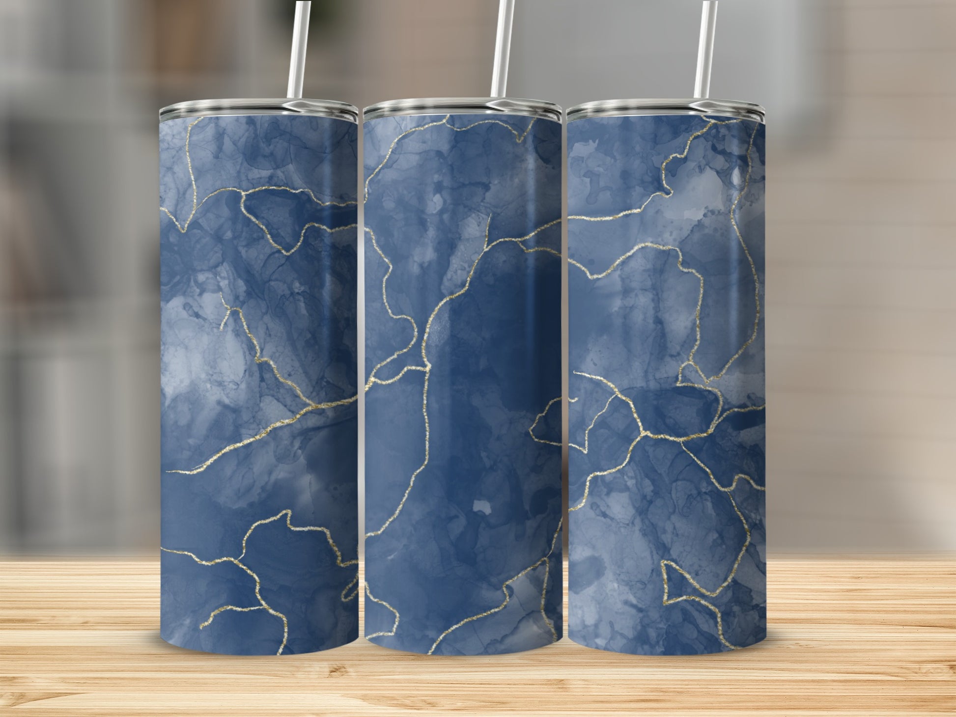 Three blue marble tumblers with gold veining and white straws.