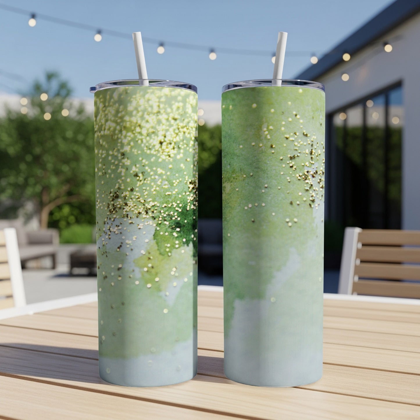 Two green tumblers with gold glitter on an outdoor table.