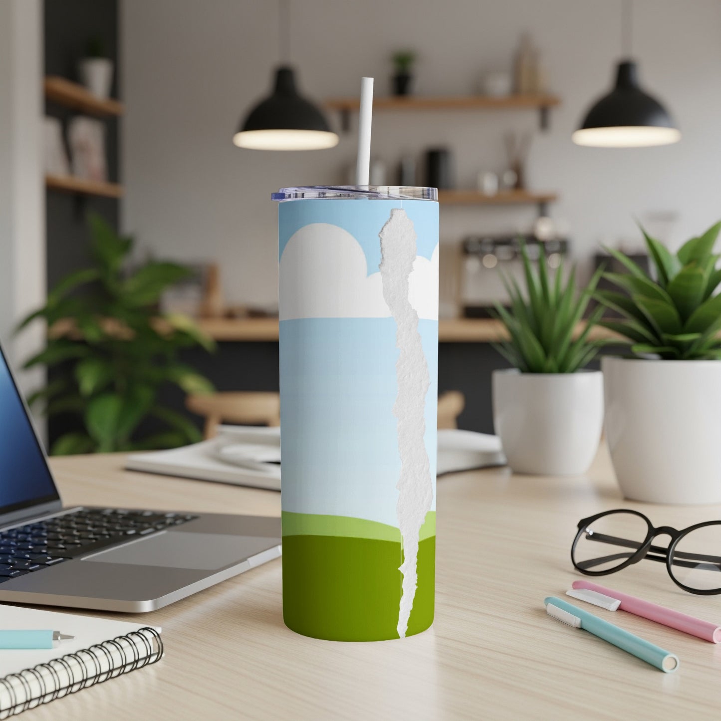 Tumbler with ripped paper effect revealing a sky and green hills design.
