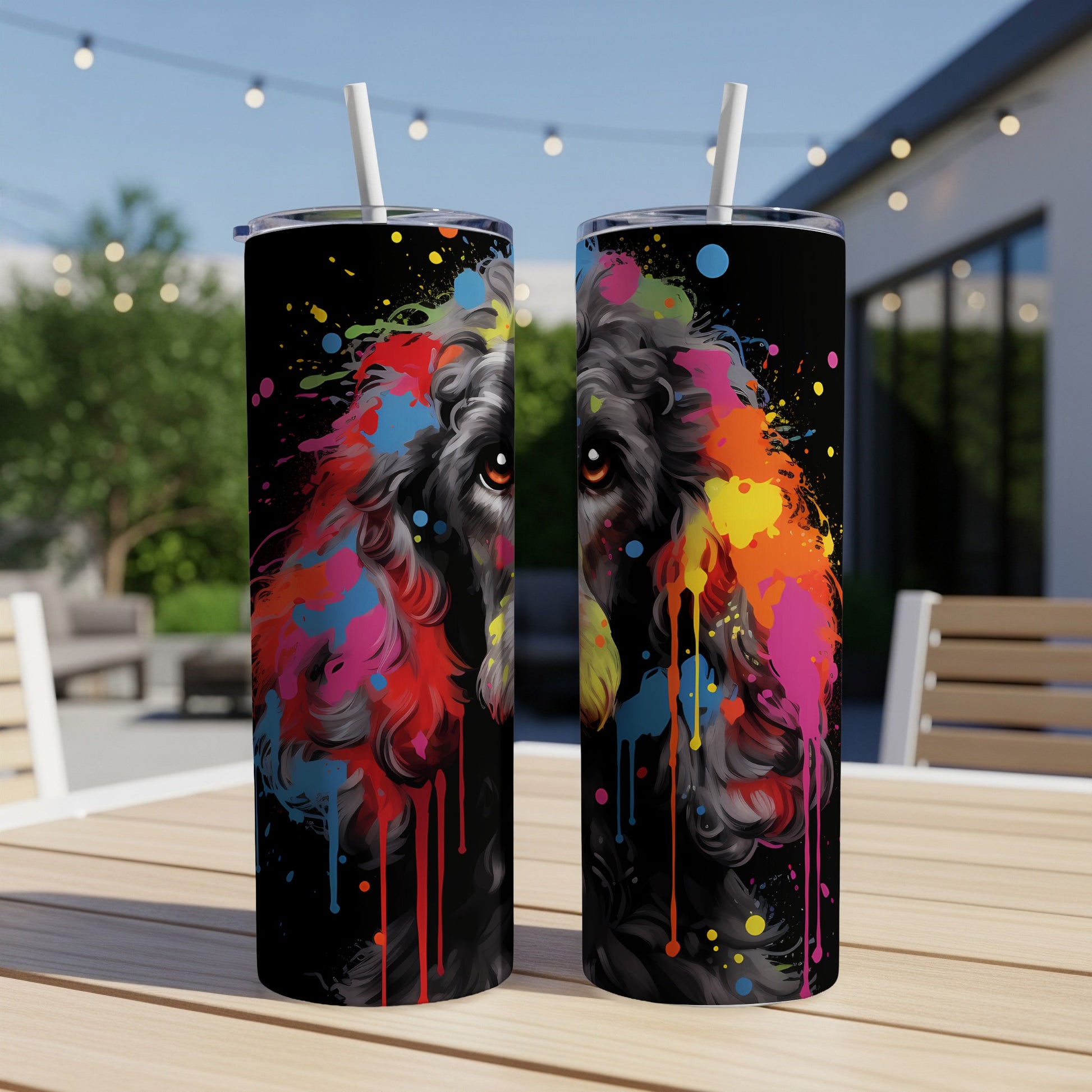Black poodle with vibrant paint splatters, two tumblers on a table.