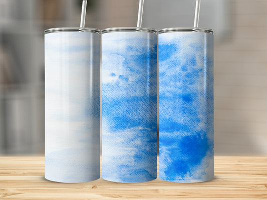 Three blue watercolor tumblers with straws stand on a wooden surface.