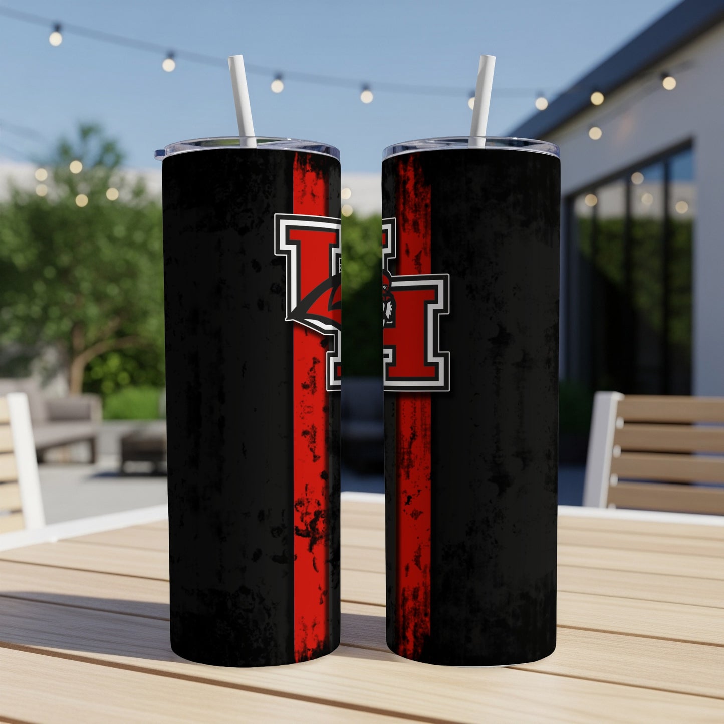 Two tumblers with black, red, and white design on a wooden table outdoors.