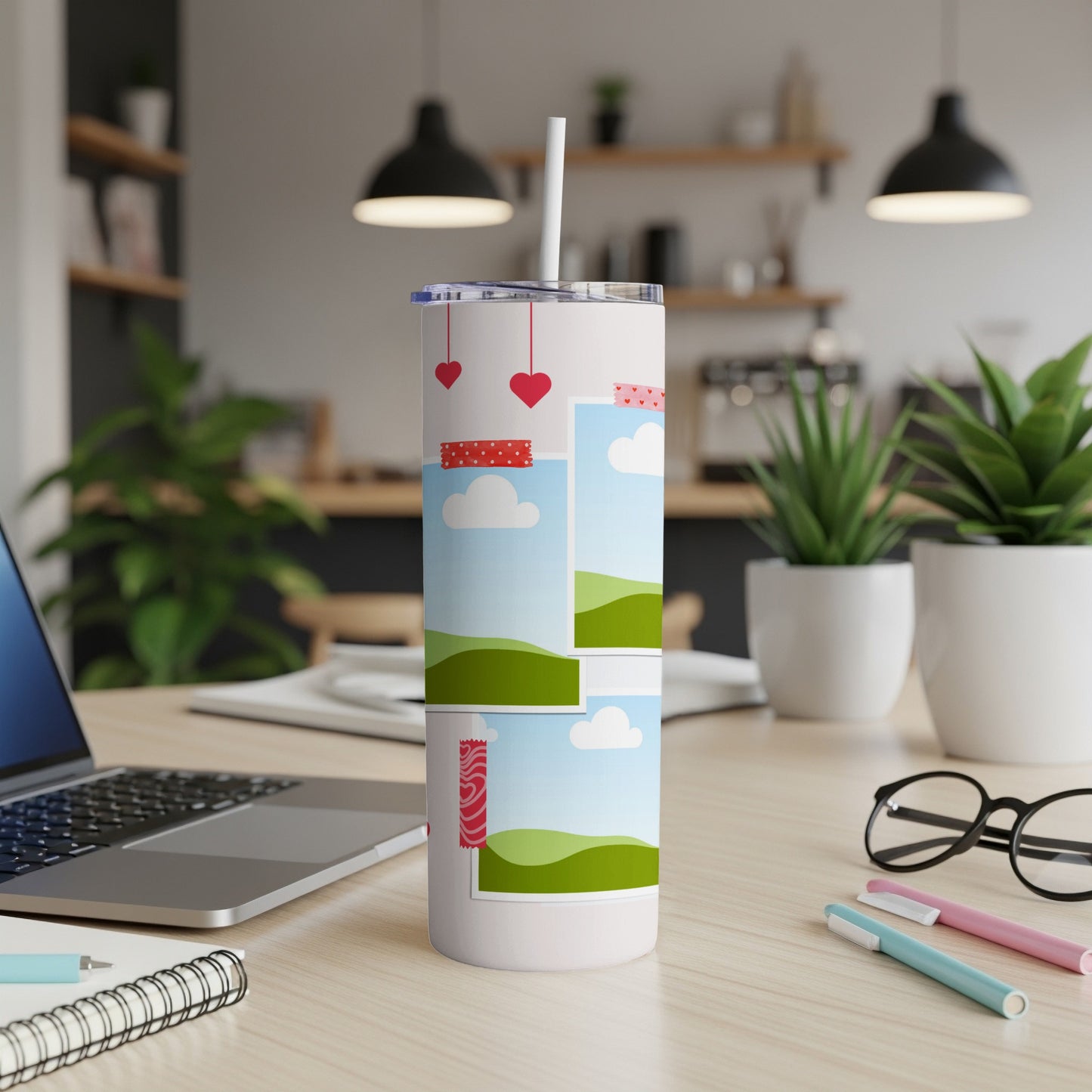 White tumbler with heart and photo frame designs, next to a laptop.