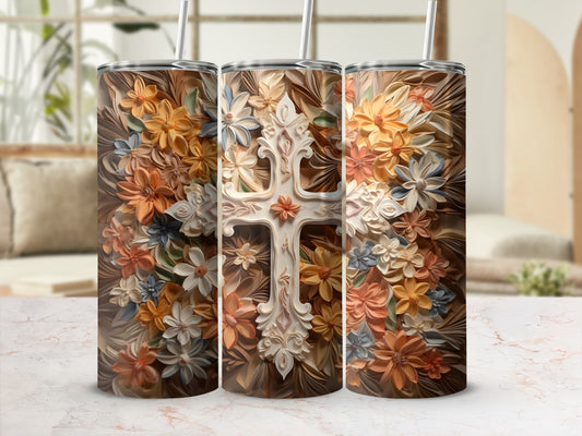 Floral cross tumbler with straw, warm tones on brown background.