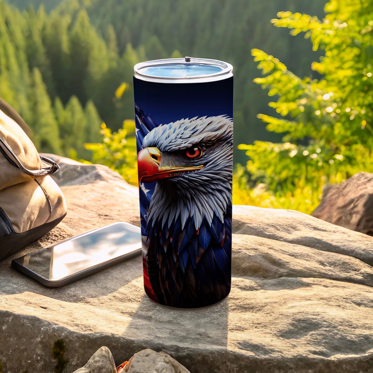 Eagle with American flag design on a tumbler next to phone and bag.