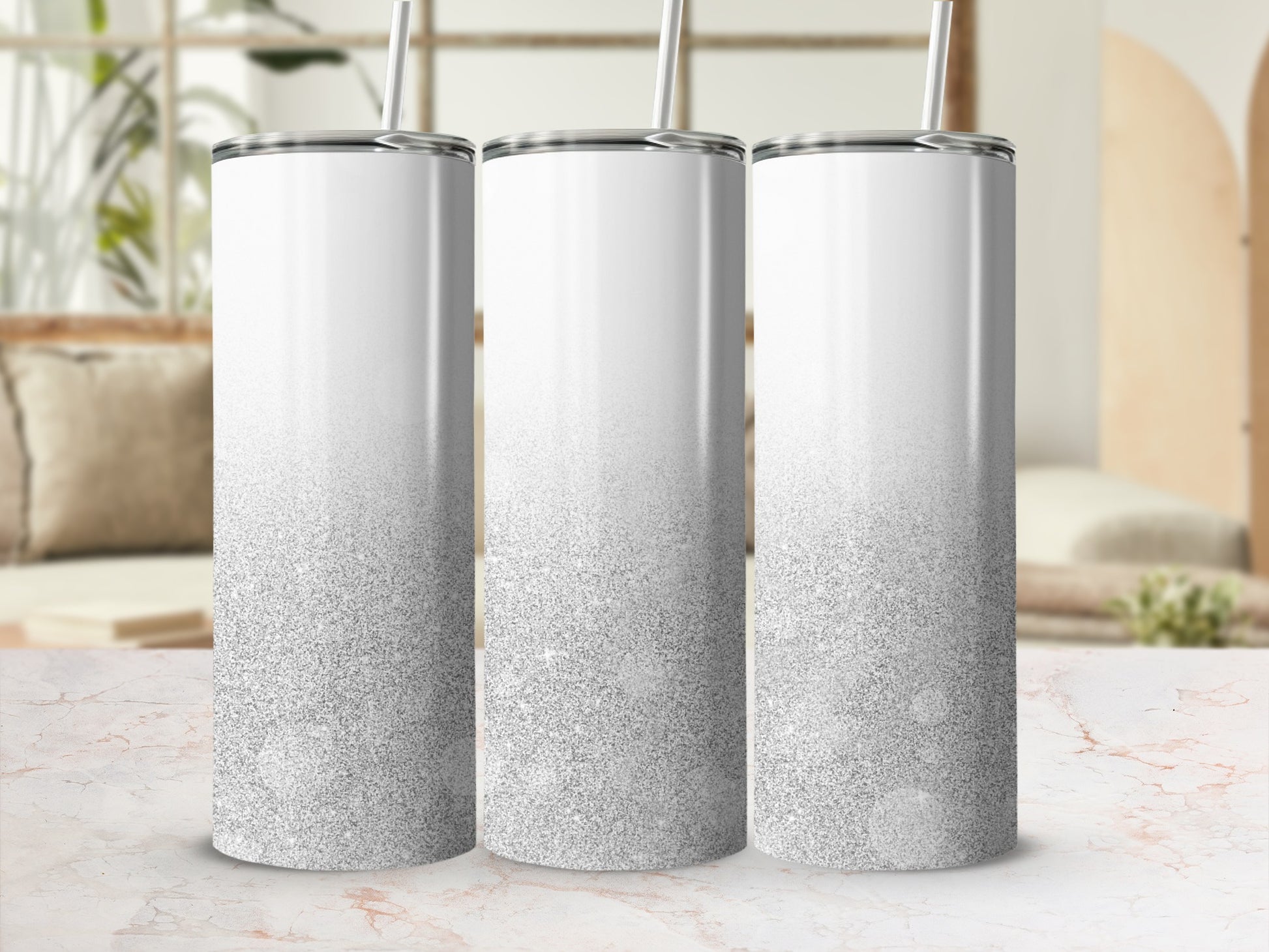 Three white tumblers with silver glitter gradient stand on a marble countertop.