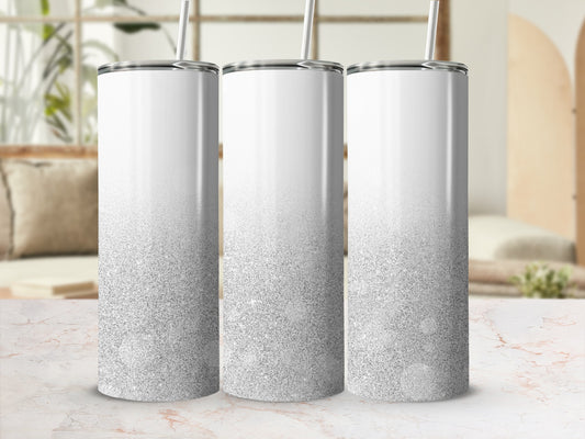 Three white tumblers with silver glitter gradient stand on a marble countertop.