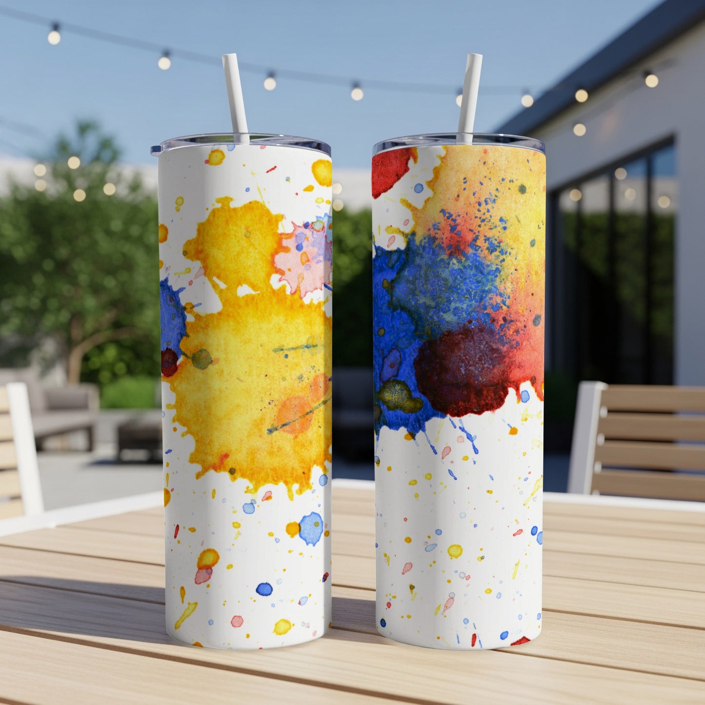 Two tumblers with colorful watercolor splashes on a wooden table.