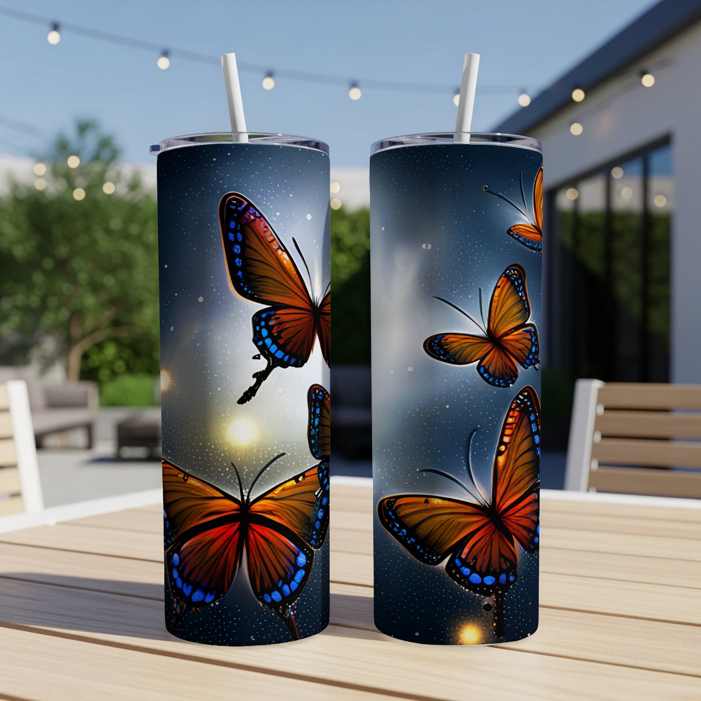 Two tumblers with a vibrant orange butterfly design sit on a wooden table outdoors.