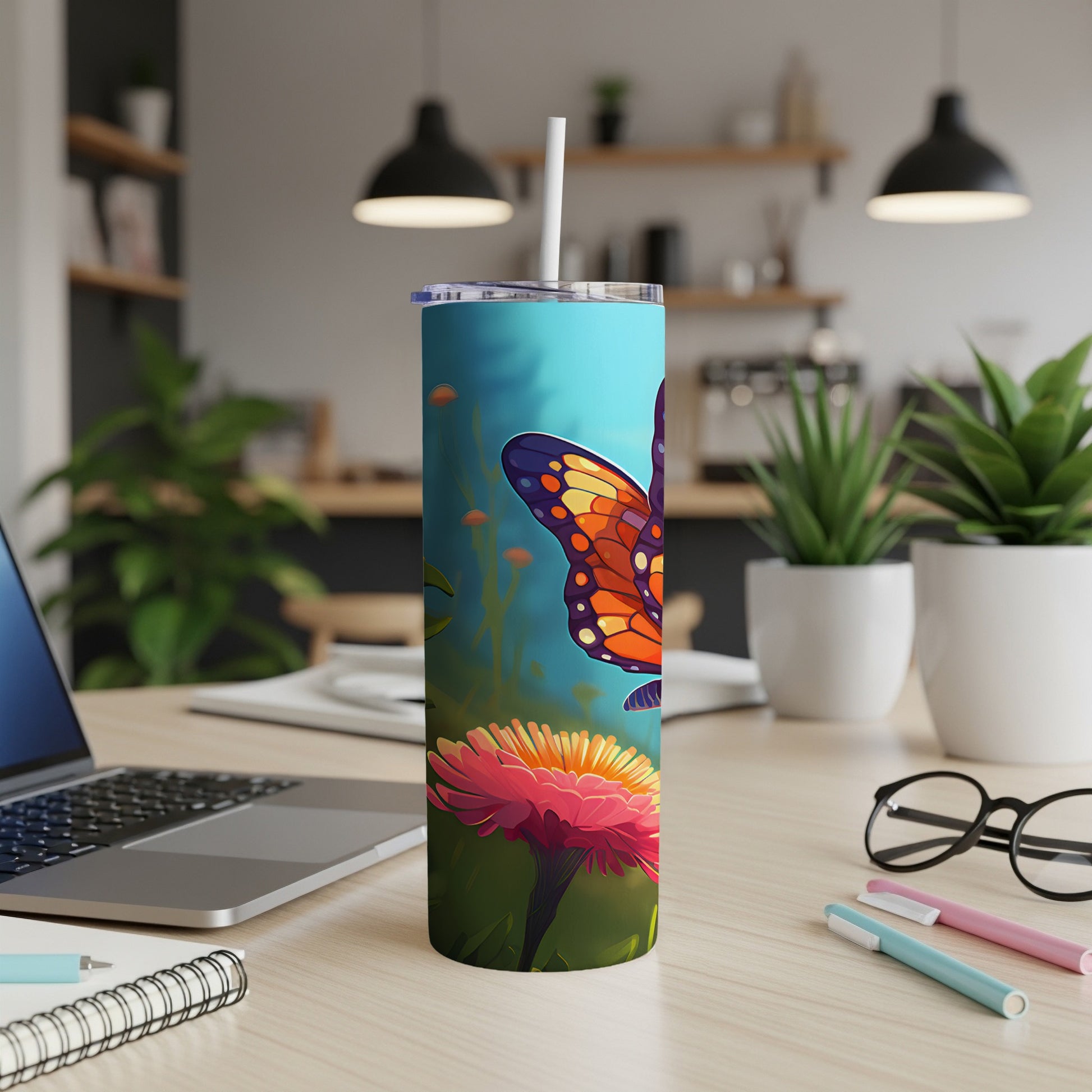 Tumbler featuring a butterfly on a pink flower, with a laptop and office supplies in background.