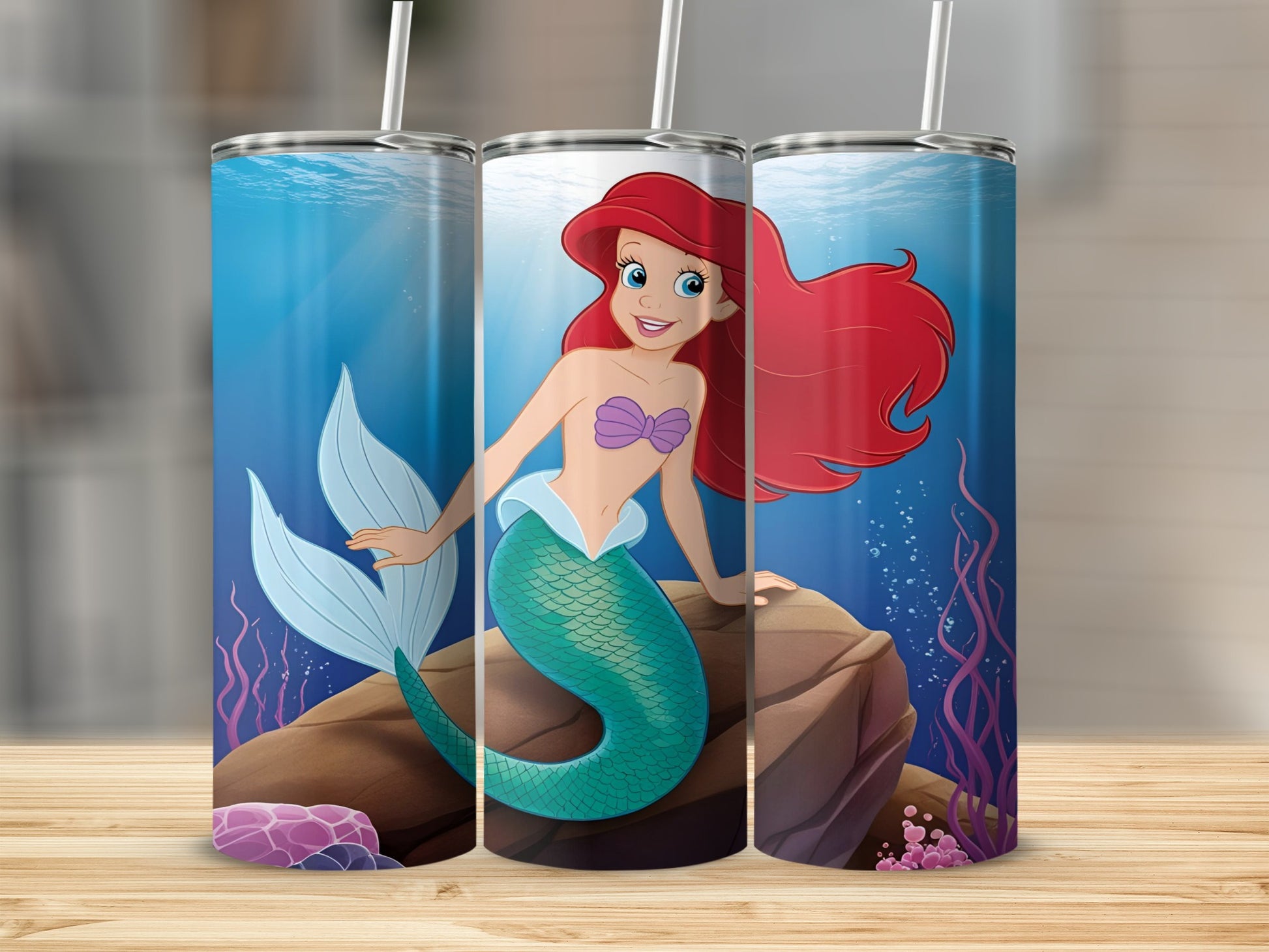 Ariel the mermaid sits on a rock underwater with coral and bubbles.