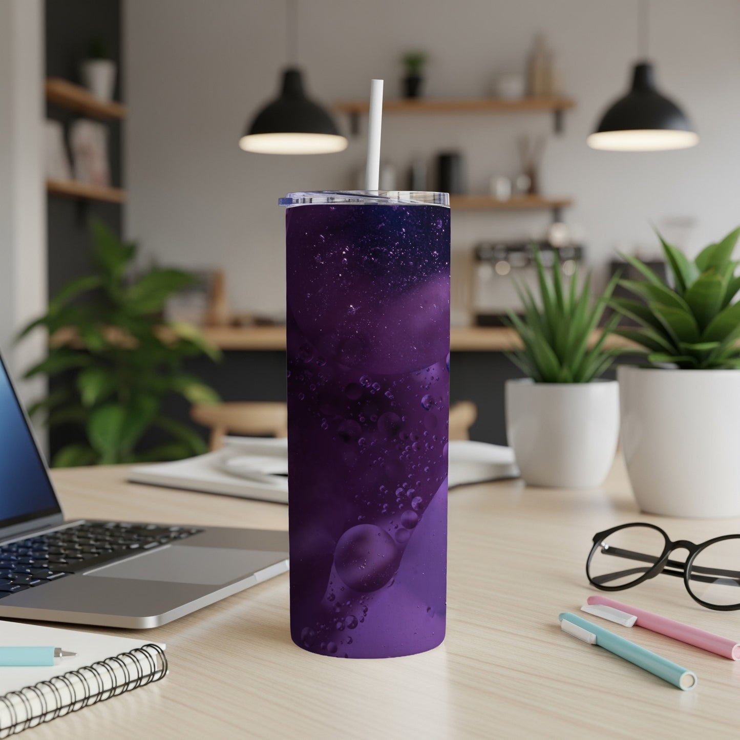 Purple galaxy pattern tumbler with a white straw on a desk.