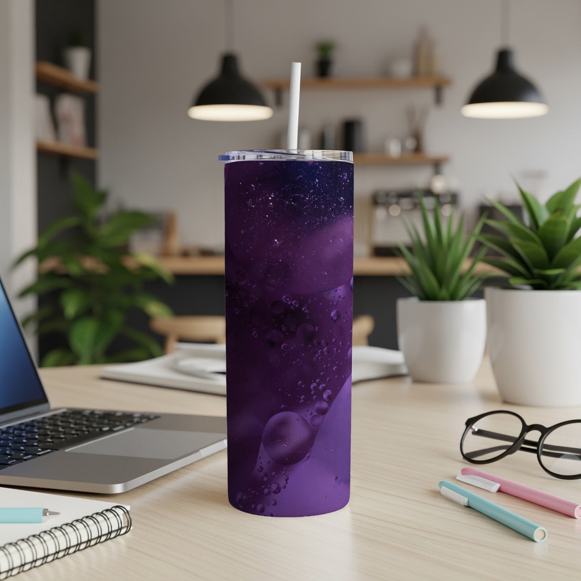 Purple galaxy pattern tumbler with a white straw on a desk.