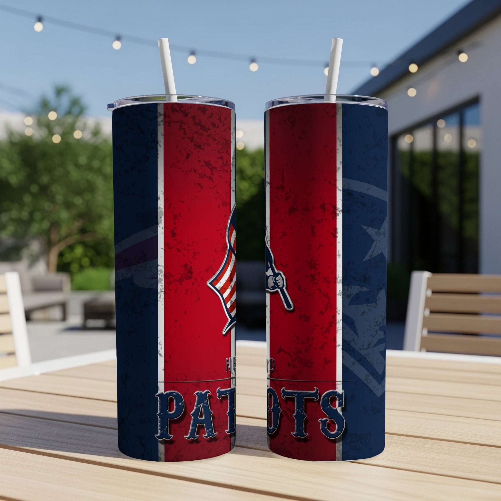 Two Patriots-themed tumblers with straws on a wooden table outdoors.