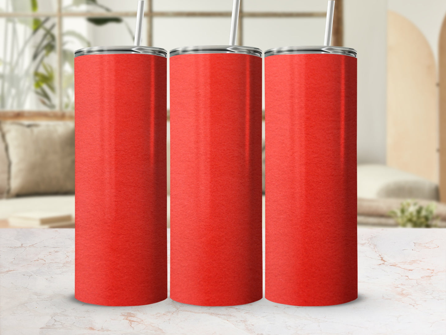 Three red tumblers with straws on a marble countertop, with a blurred background.