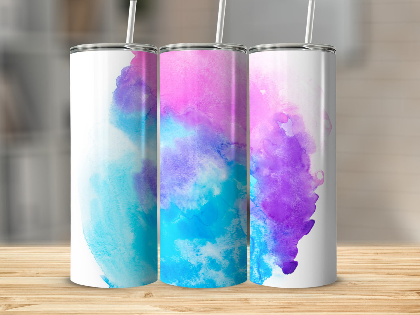Three tumblers with colorful watercolor designs in pink, blue, and purple.
