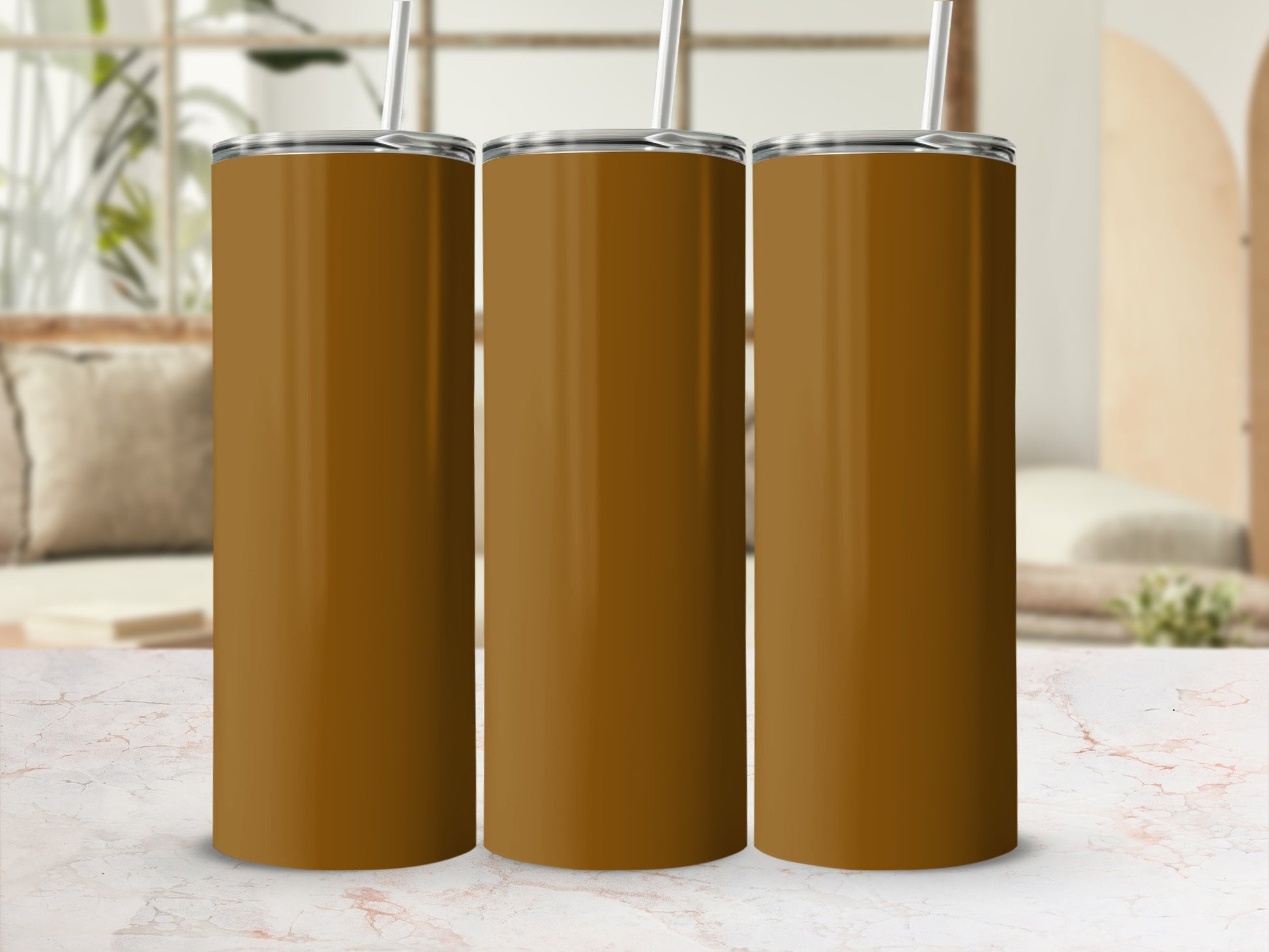 Three tall, brown tumblers with straws on a marble surface.