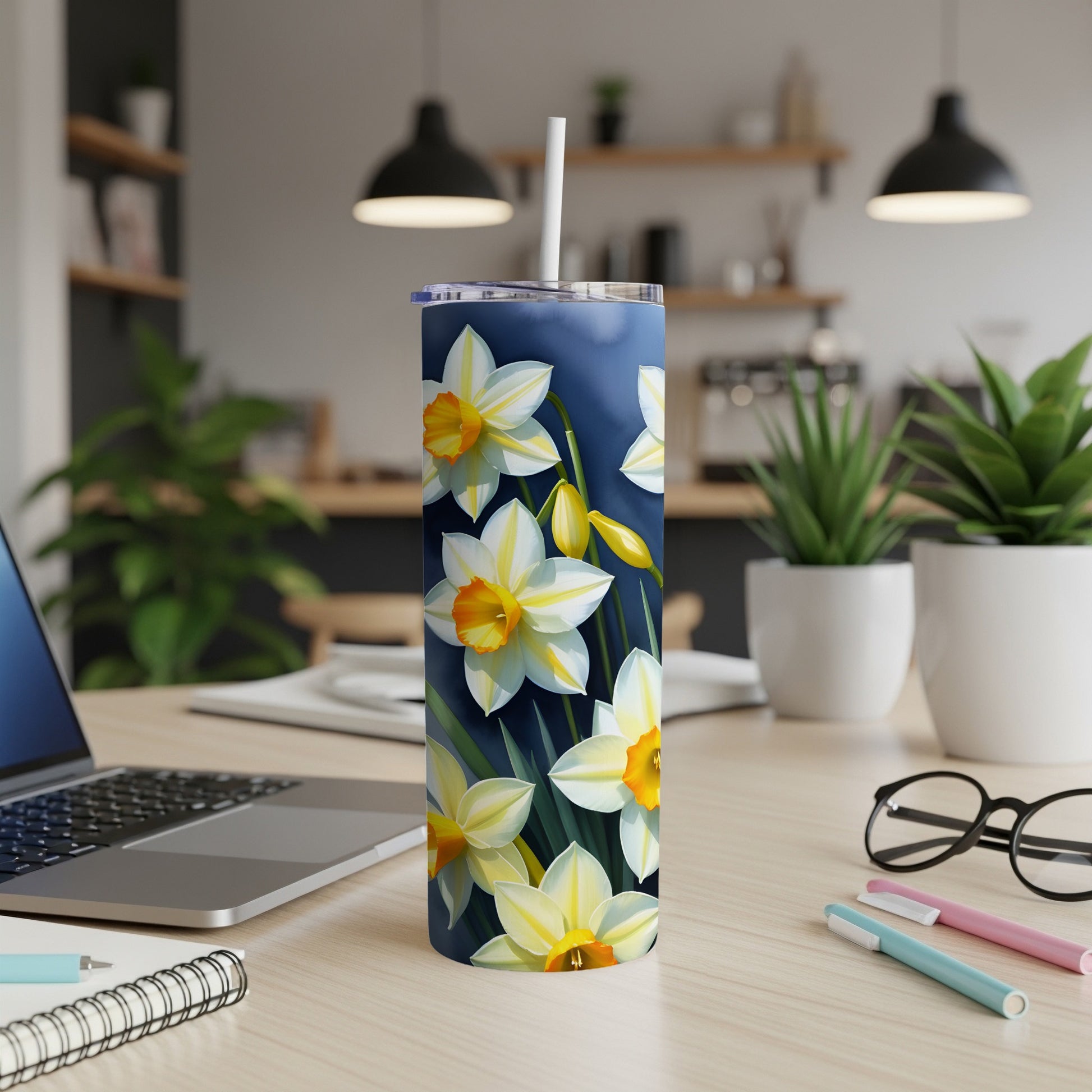 White and yellow daffodils on a dark blue floral tumbler with a straw.