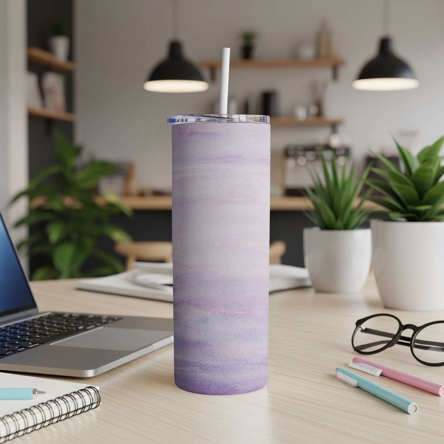 Marble pattern tumbler with straw on desk with laptop and pens.